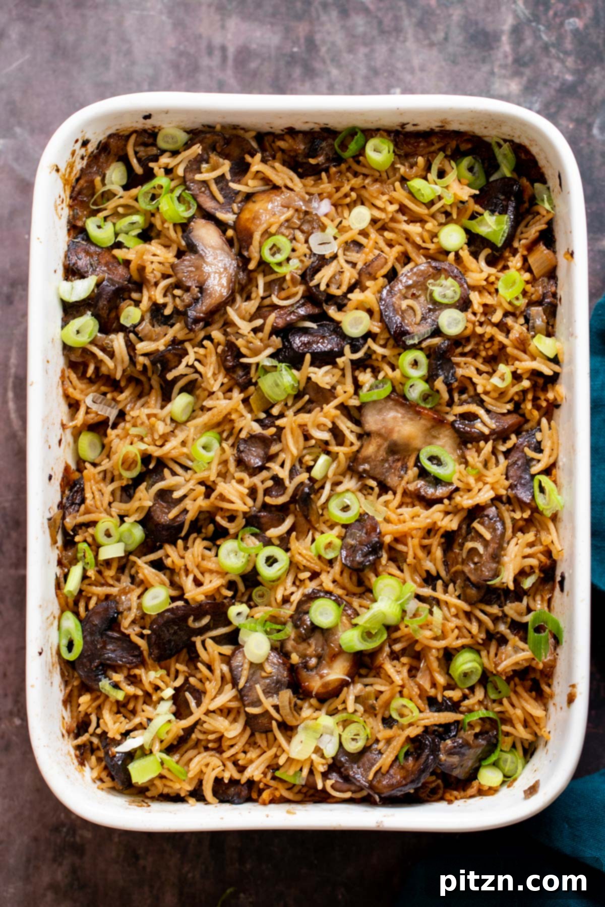 A casserole dish filled with freshly baked vegan mushroom rice, showcasing its golden-brown mushrooms and perfectly cooked grains.