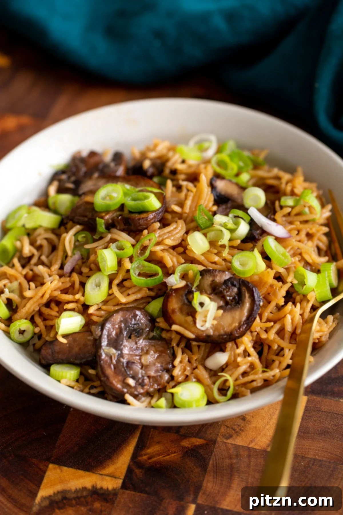 A plate with a generous portion of baked mushroom rice, garnished with vibrant sliced green onions for a fresh touch.