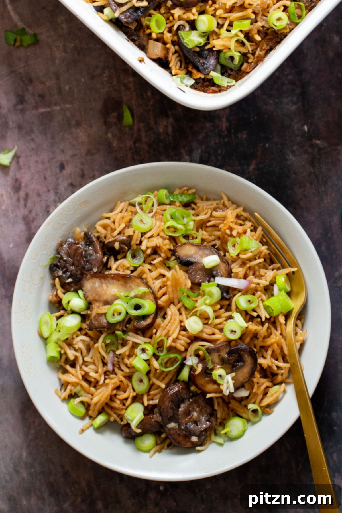 A plate of baked mushroom rice, beautifully garnished with vibrant green onions, ready to be served.