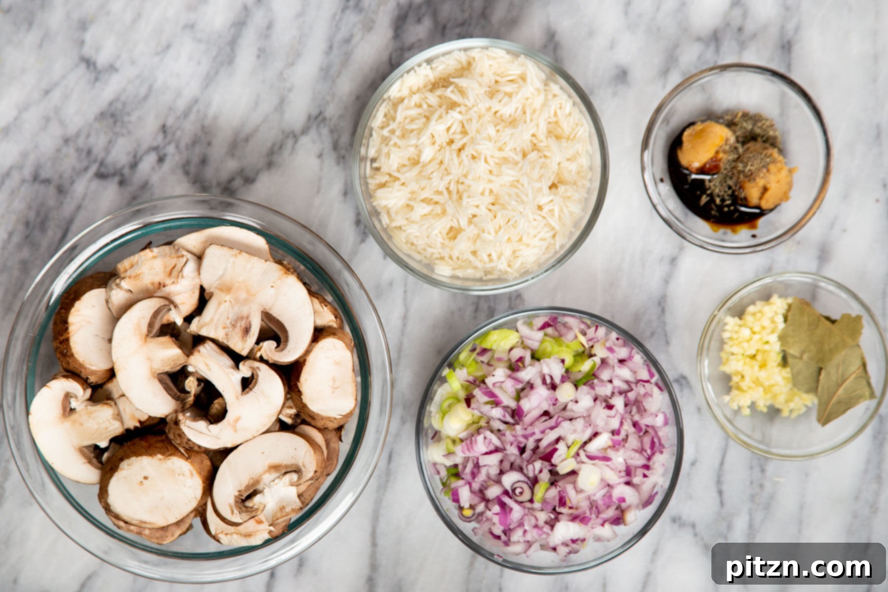 Various fresh ingredients laid out, including sliced mushrooms, onions, garlic, and basmati rice, ready for making baked mushroom rice.