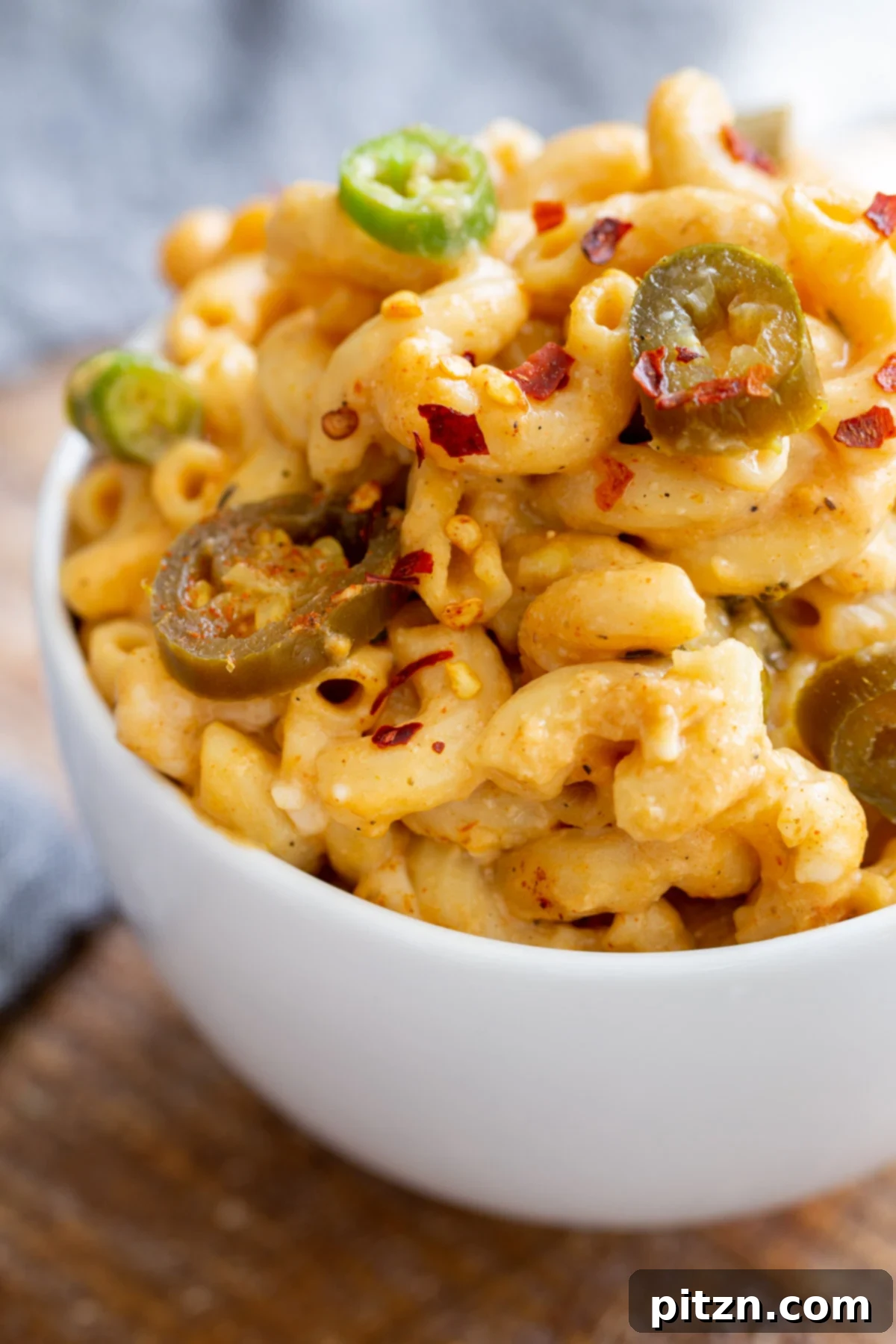 Fiery Vegan Skillet Mac and Cheese 2 A generous serving of vegan mac and cheese, richly topped with vibrant green jalapeño slices, presented in a clean white bowl.