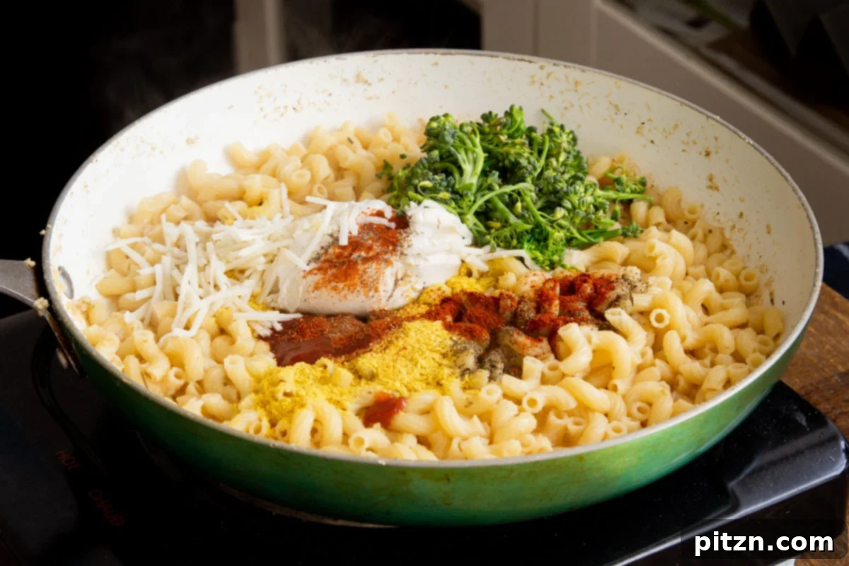 Fiery Vegan Skillet Mac and Cheese 11 A skillet showcasing cooked pasta gently coated with a developing vegan mac and cheese sauce, with additional creamy ingredients being stirred in.