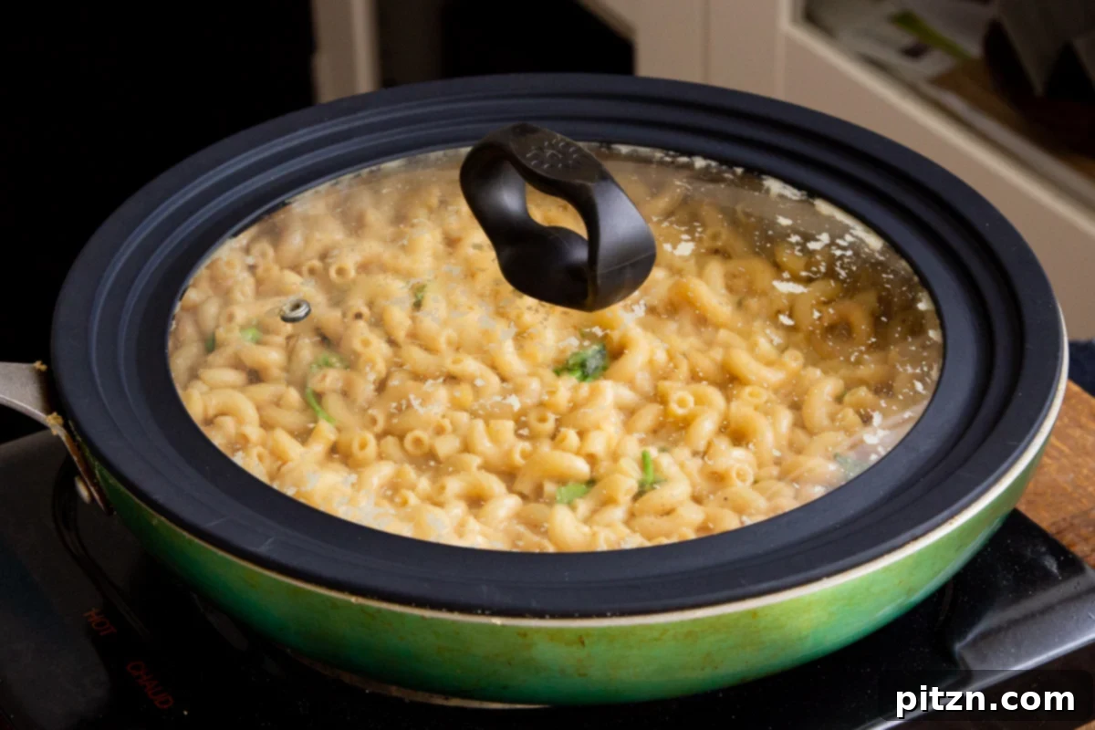 Fiery Vegan Skillet Mac and Cheese 13 A vibrant green skillet with a lid, containing vegan jalapeño mac and cheese gently simmering, allowing the flavors to meld and the sauce to thicken perfectly.
