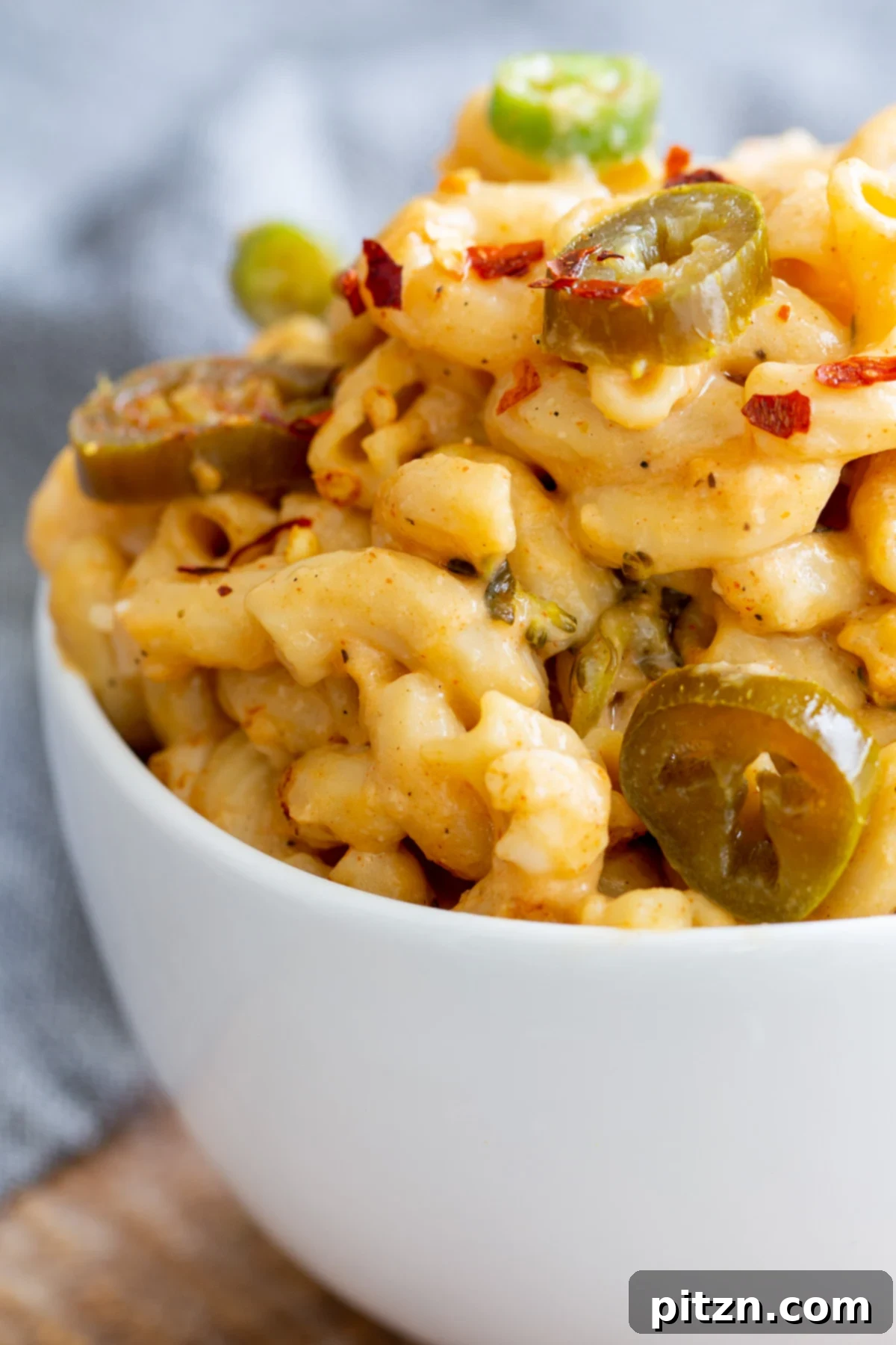 Fiery Vegan Skillet Mac and Cheese 15 A close-up view of a serving of rich, creamy vegan Jalapeño mac and cheese in a pristine white bowl, showcasing the perfect texture and vibrant toppings.