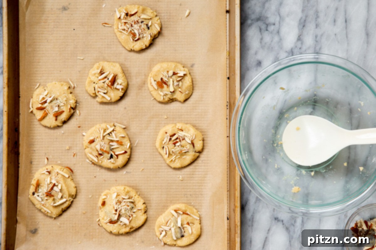 Irresistible Vegan Gluten-Free Almond Coconut Joy Cookies 12 Unbaked vegan Almond Joy cookies topped with slivered almonds on a baking sheet