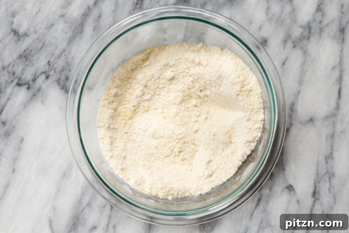 Irresistible Vegan Gluten-Free Almond Coconut Joy Cookies 9 Wet ingredients being added to the dry mixture for vegan Almond Joy cookies in a glass bowl