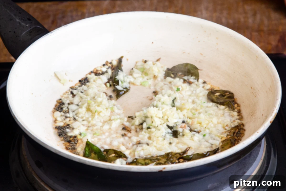 Chataka Dal: Spicy Maharashtrian Toor Dal 10 Finely chopped garlic and other aromatic tempering ingredients sizzling in a small skillet, creating a fragrant base for Chataka Dal.