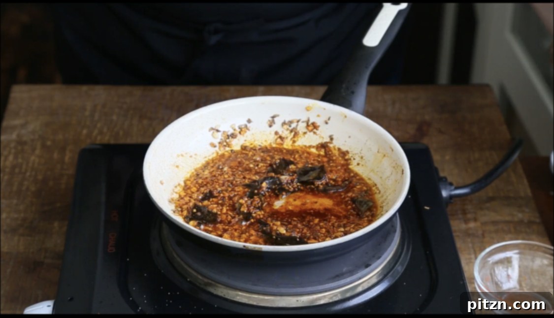 Chataka Dal: Spicy Maharashtrian Toor Dal 11 A vibrant mix of finely ground spices, including bright red chili powder and turmeric, being carefully added to hot oil in a pristine white pan for the tempering process of Chataka Dal.