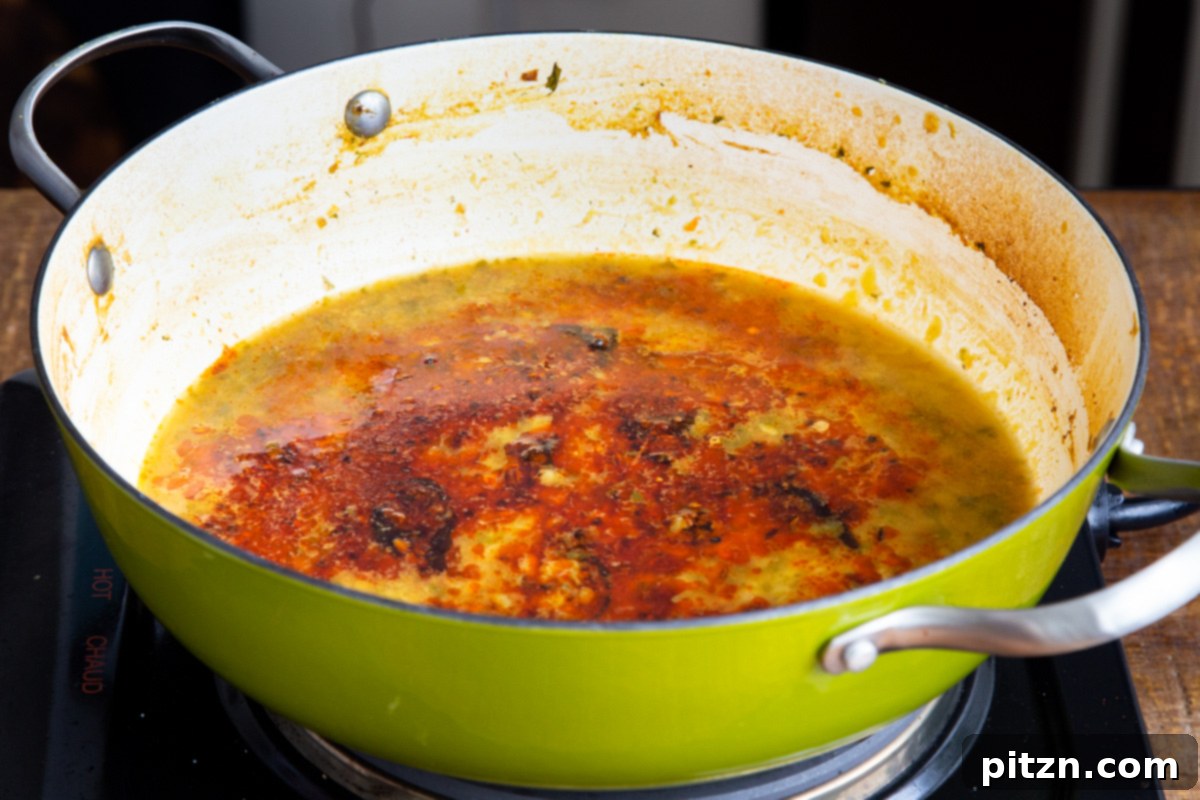 Chataka Dal: Spicy Maharashtrian Toor Dal 12 Sizzling seasoned oil with a beautiful blend of spices being carefully poured into a pot of simmering Chataka Dal, creating an aromatic swirl of flavor and color. This captures the final, crucial step of tadka.