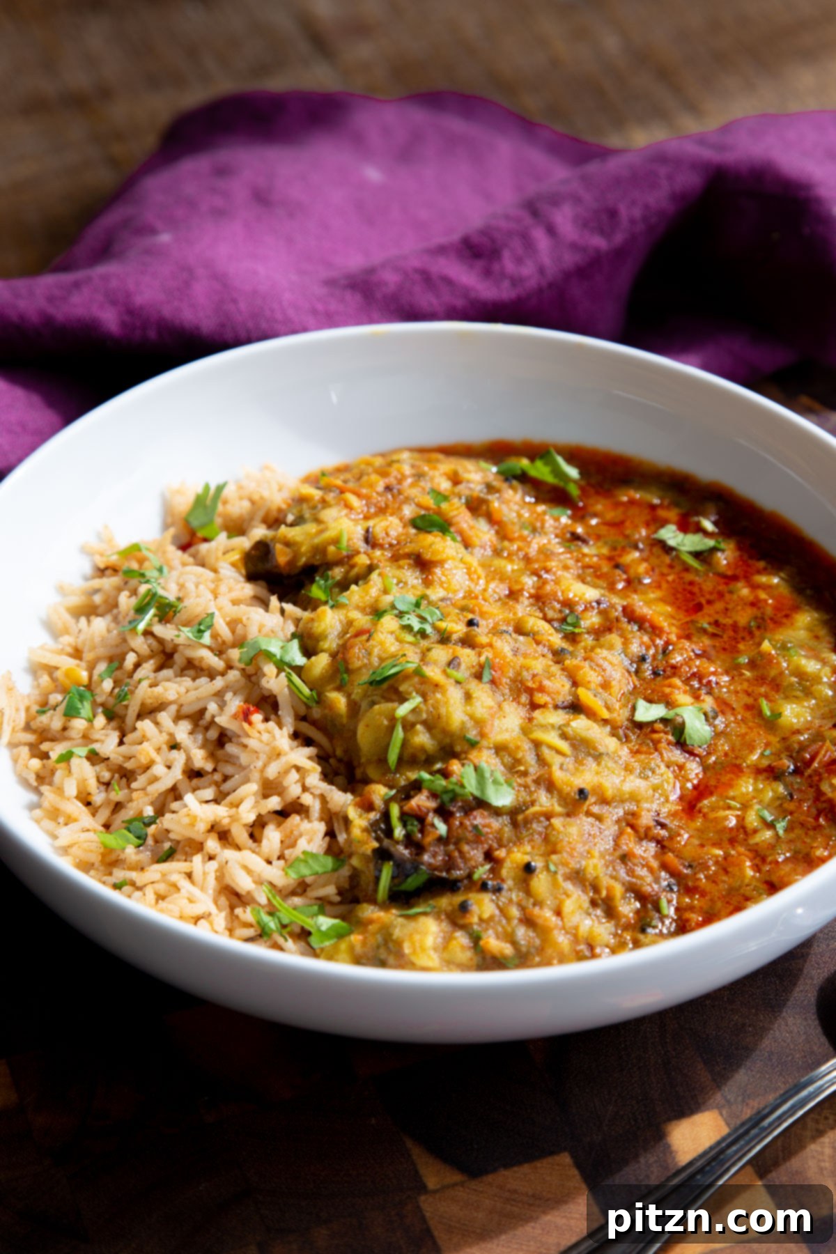 Chataka Dal: Spicy Maharashtrian Toor Dal 5 A beautiful overhead shot of Chataka Dal served with fluffy brown rice in a white bowl, garnished with fresh herbs and a slice of lemon. This image highlights a complete and inviting Indian meal.