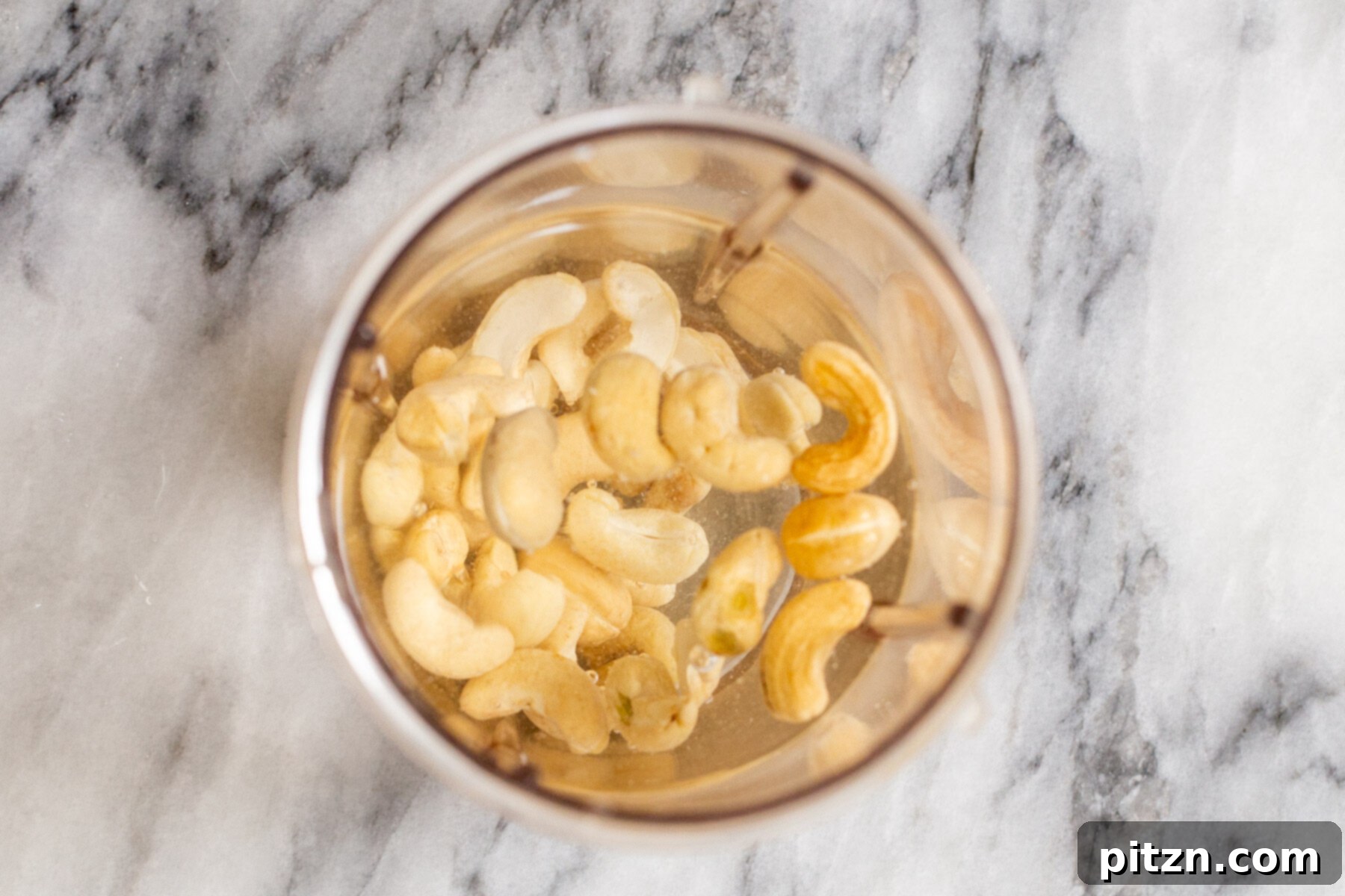 Plant-Based Boston Dream Cake 14 Raw cashews soaking in water in a blender jar, preparing for blending into creamy vegan custard.