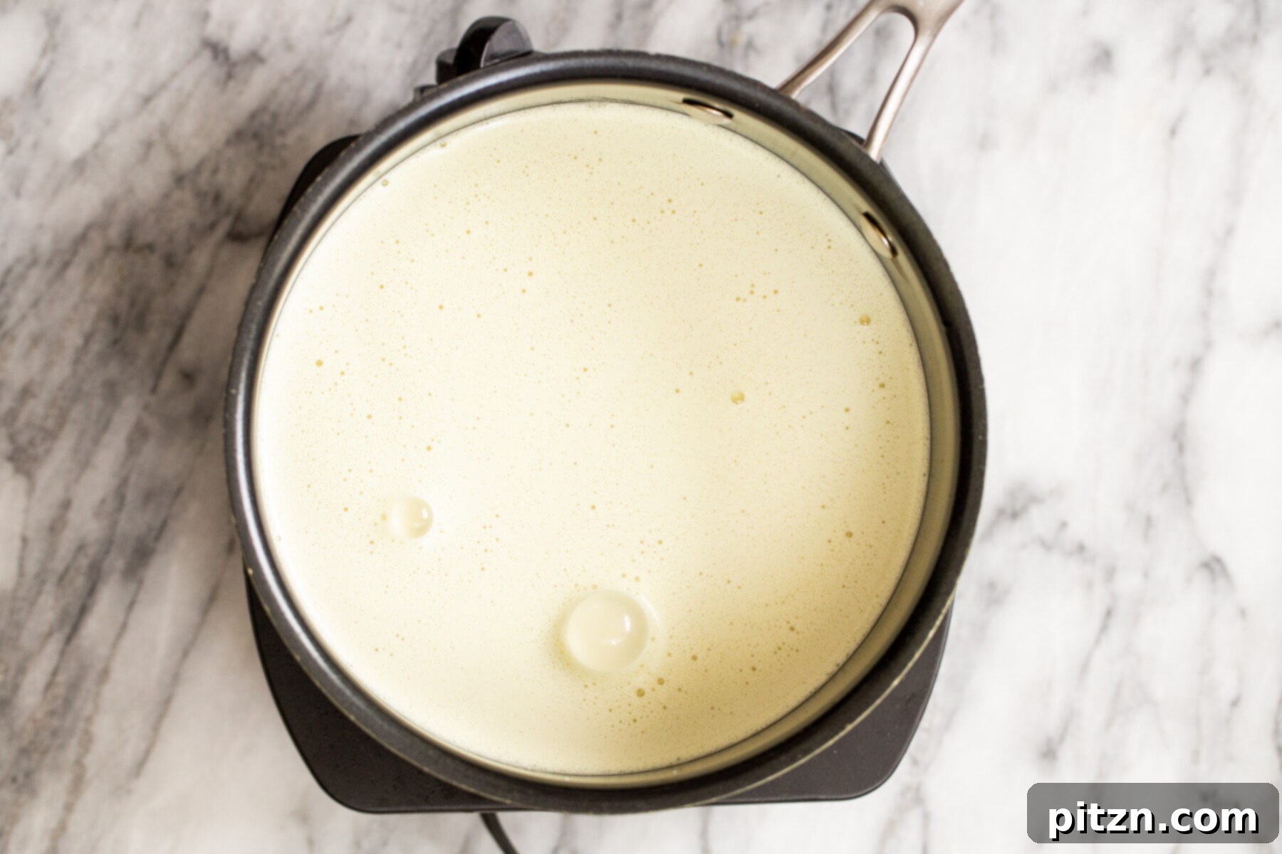 Plant-Based Boston Dream Cake 17 Vegan custard ingredients gently heating in a saucepan on a stove, with a whisk nearby, indicating the cooking process.
