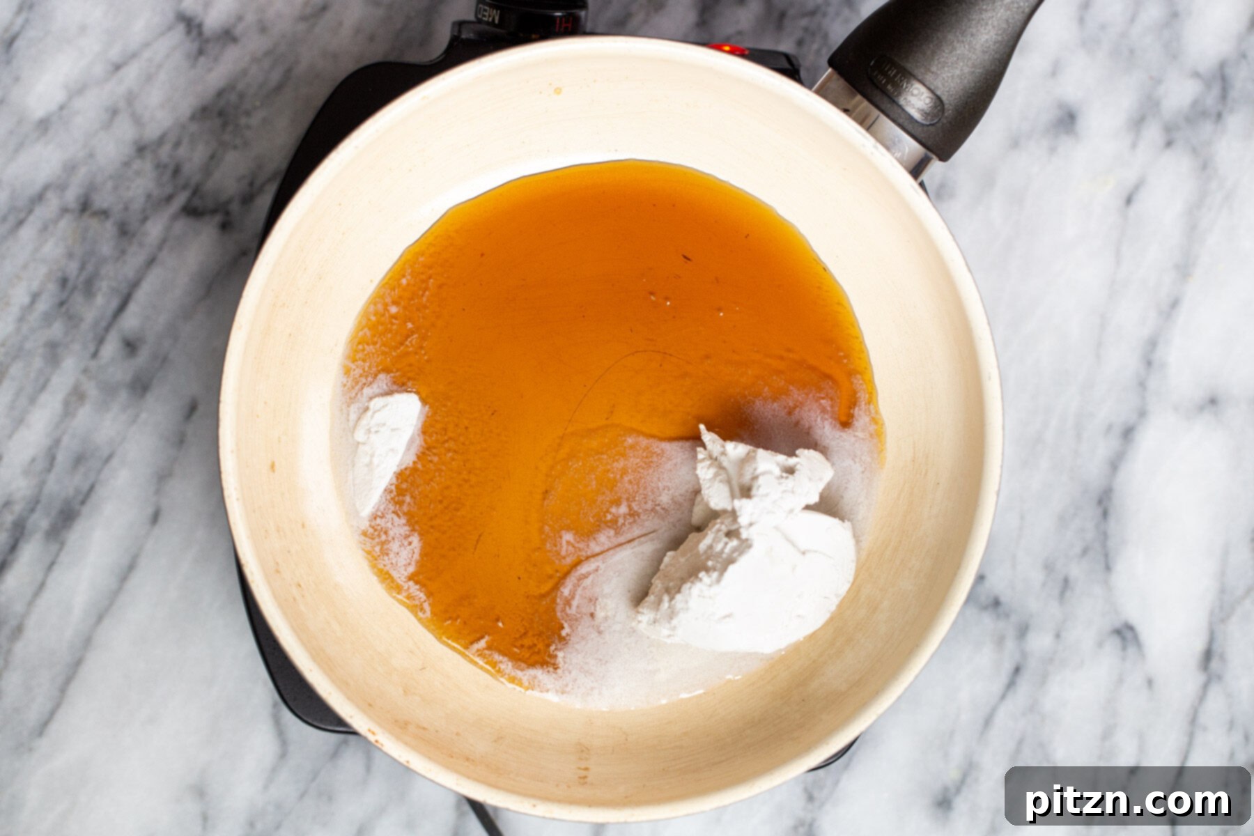 Plant-Based Boston Dream Cake 20 Maple syrup being poured into a sauté pan with coconut cream, creating the liquid base for the decadent chocolate ganache.