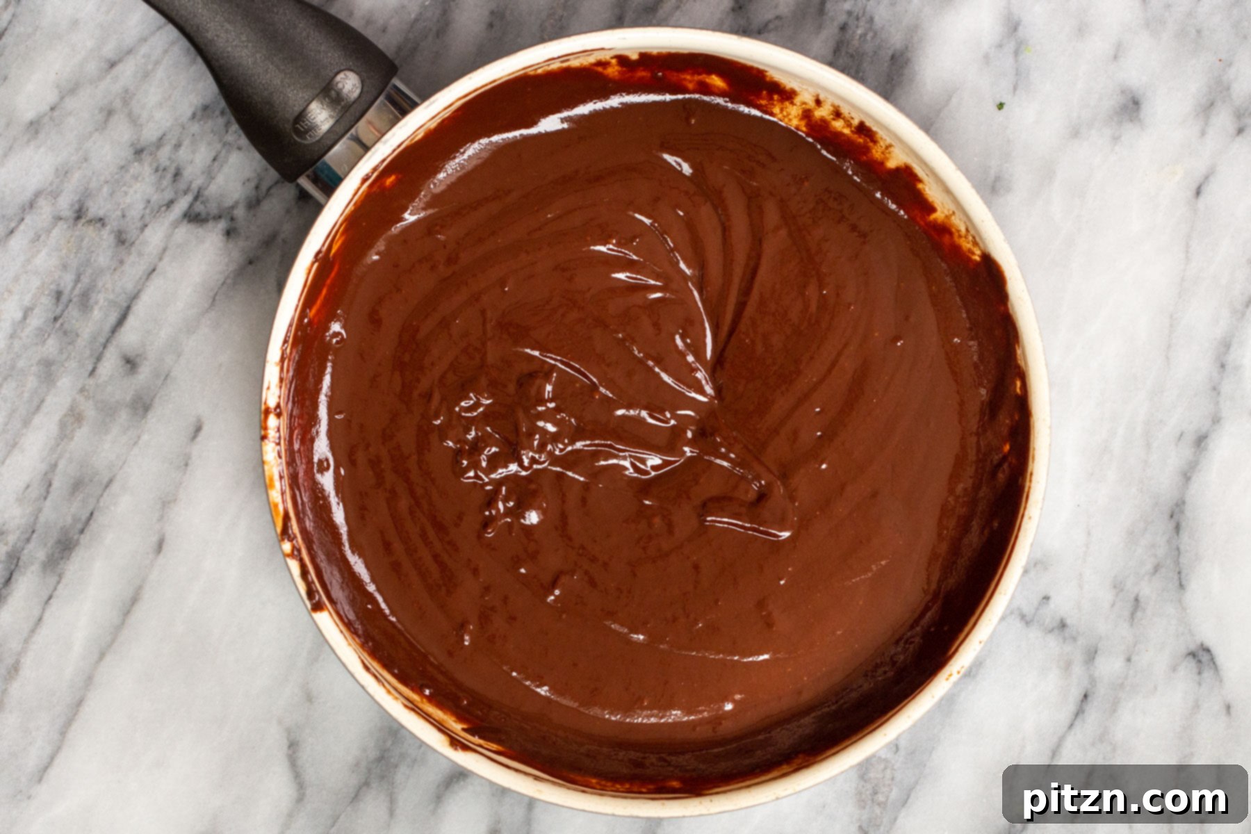 Plant-Based Boston Dream Cake 23 A smooth, dark, and glossy vegan chocolate glaze in a pan, perfectly melted and whisked, ready to be poured over the cake.