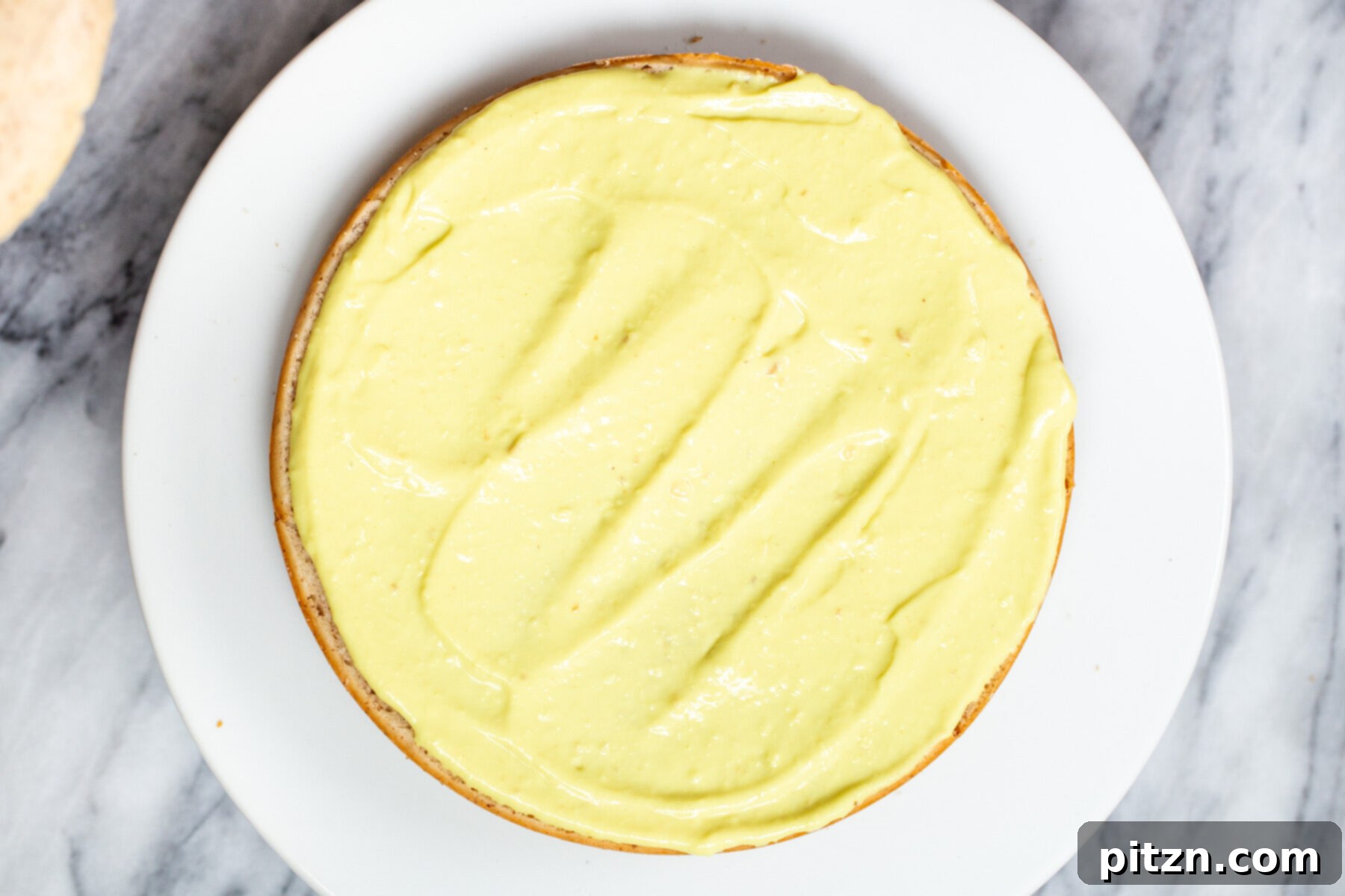 Plant-Based Boston Dream Cake 26 The vegan Boston Cream Pie cake in the process of being assembled, with the second cake layer placed on top of the custard-filled bottom layer.