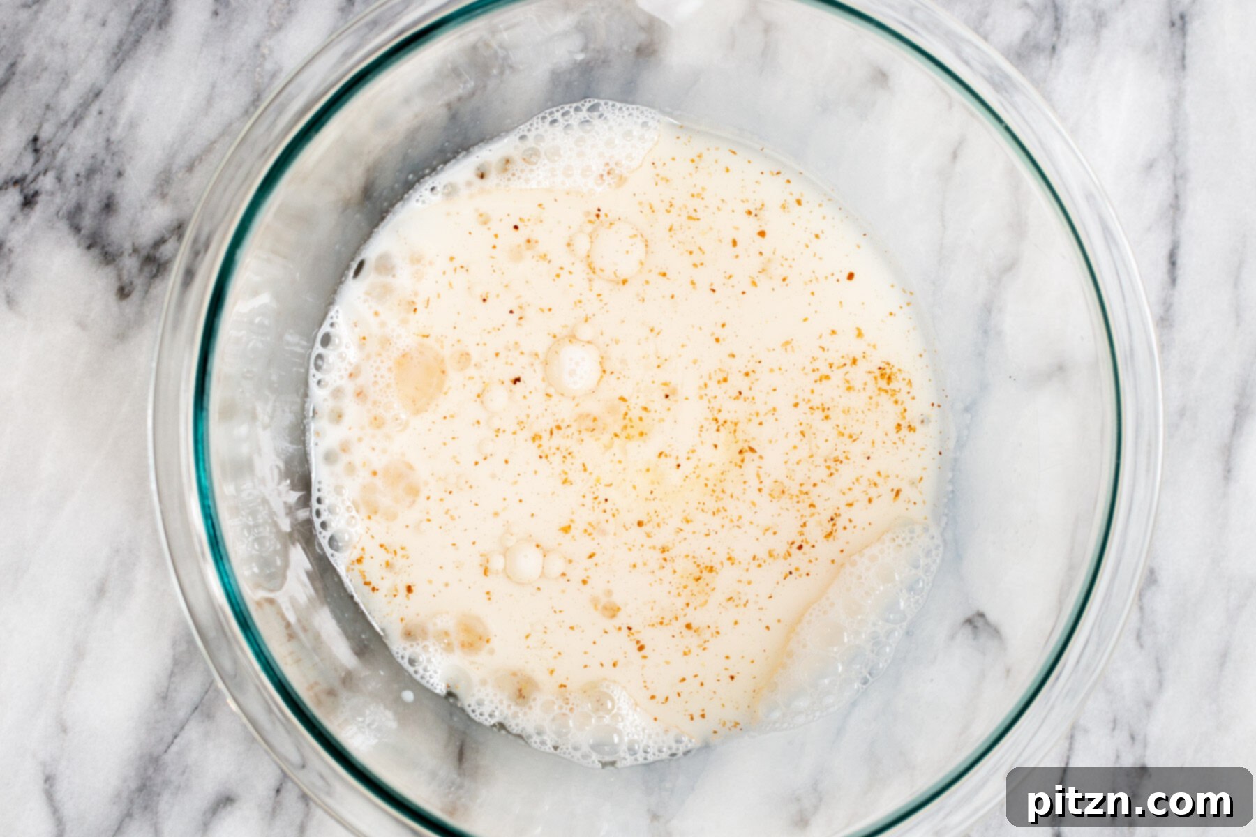 Plant-Based Boston Dream Cake 7 Liquid ingredients for vegan Boston Cream Pie cake, including non-dairy milk, applesauce, vinegar, oil, and vanilla extract, combined in a clear glass bowl.