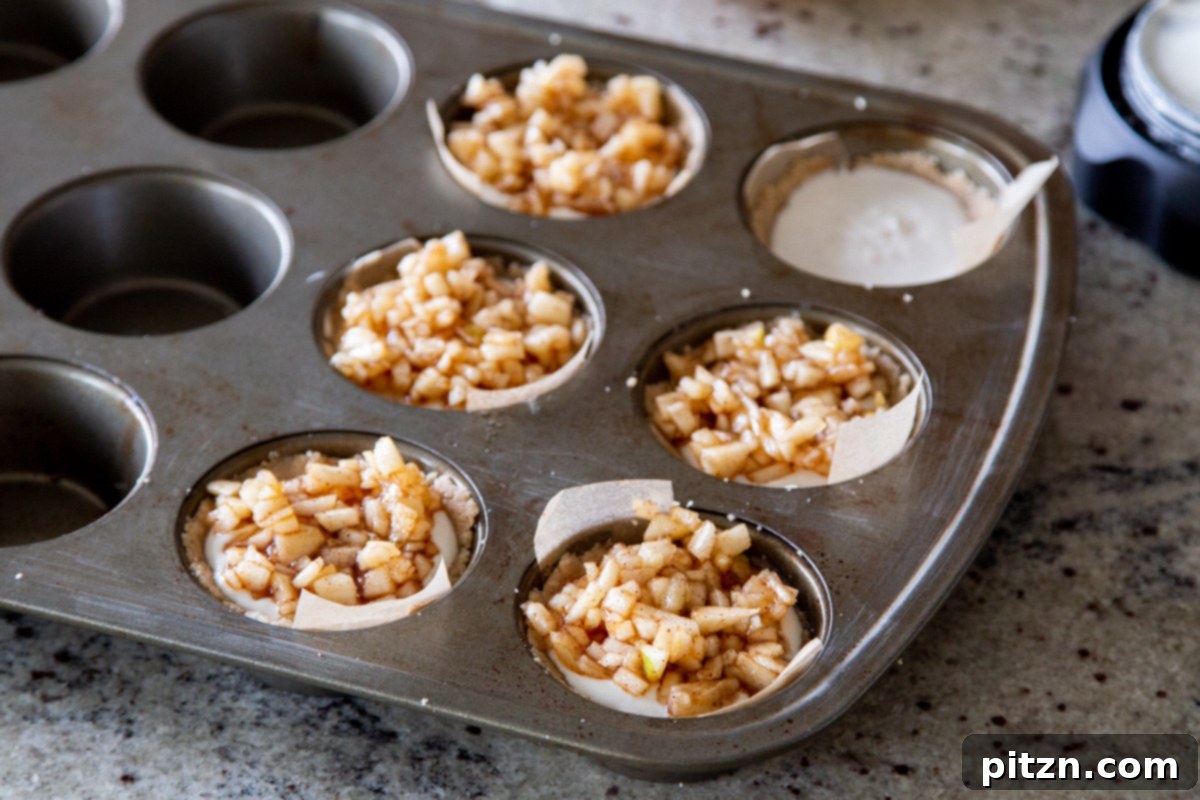 Mini Apple Pie Cheesecake Delights 15 A muffin tin filled with mini vegan apple cheesecakes, beautifully golden and ready to be removed from the oven