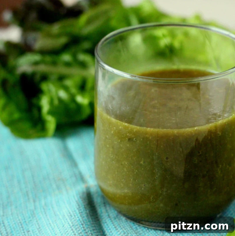 A vibrant green smoothie in a glass, surrounded by fresh ingredients like chard, lettuce, and pears.