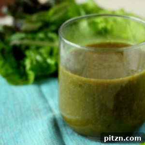 A green smoothie in a short glass, on a light blue background