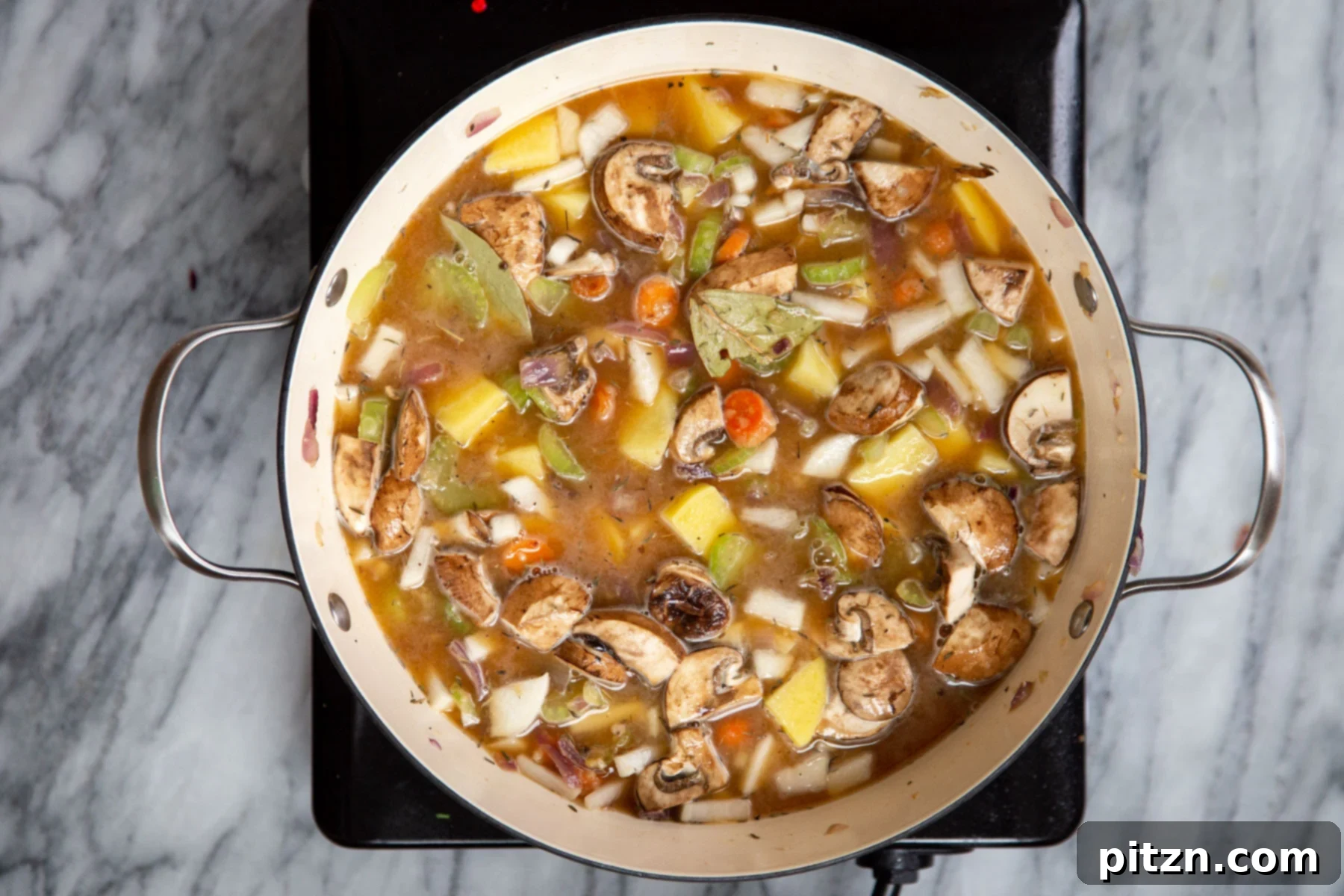 A pot of vegan Irish stew simmering gently on a hot plate, its rich aroma filling the kitchen.