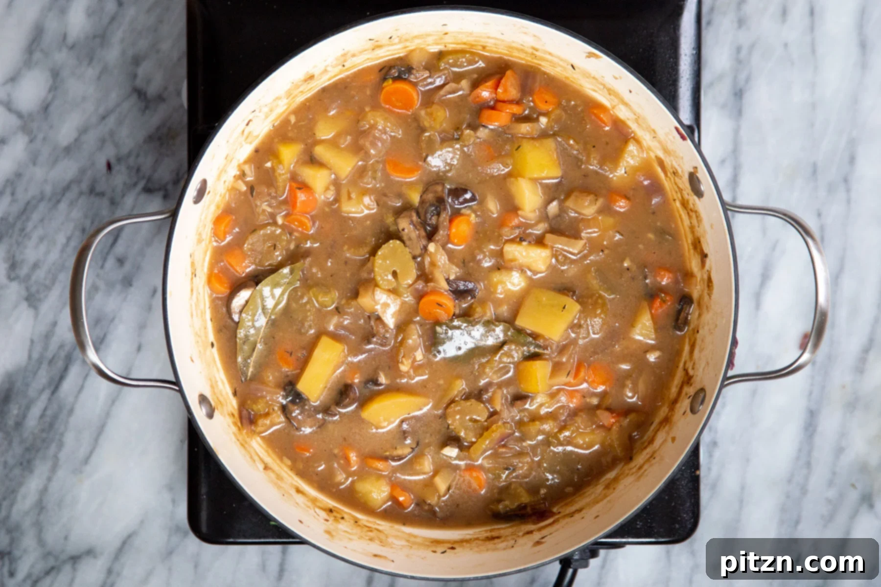 A pot of Irish stew resting on a cooking element, ready for final garnishing and serving.