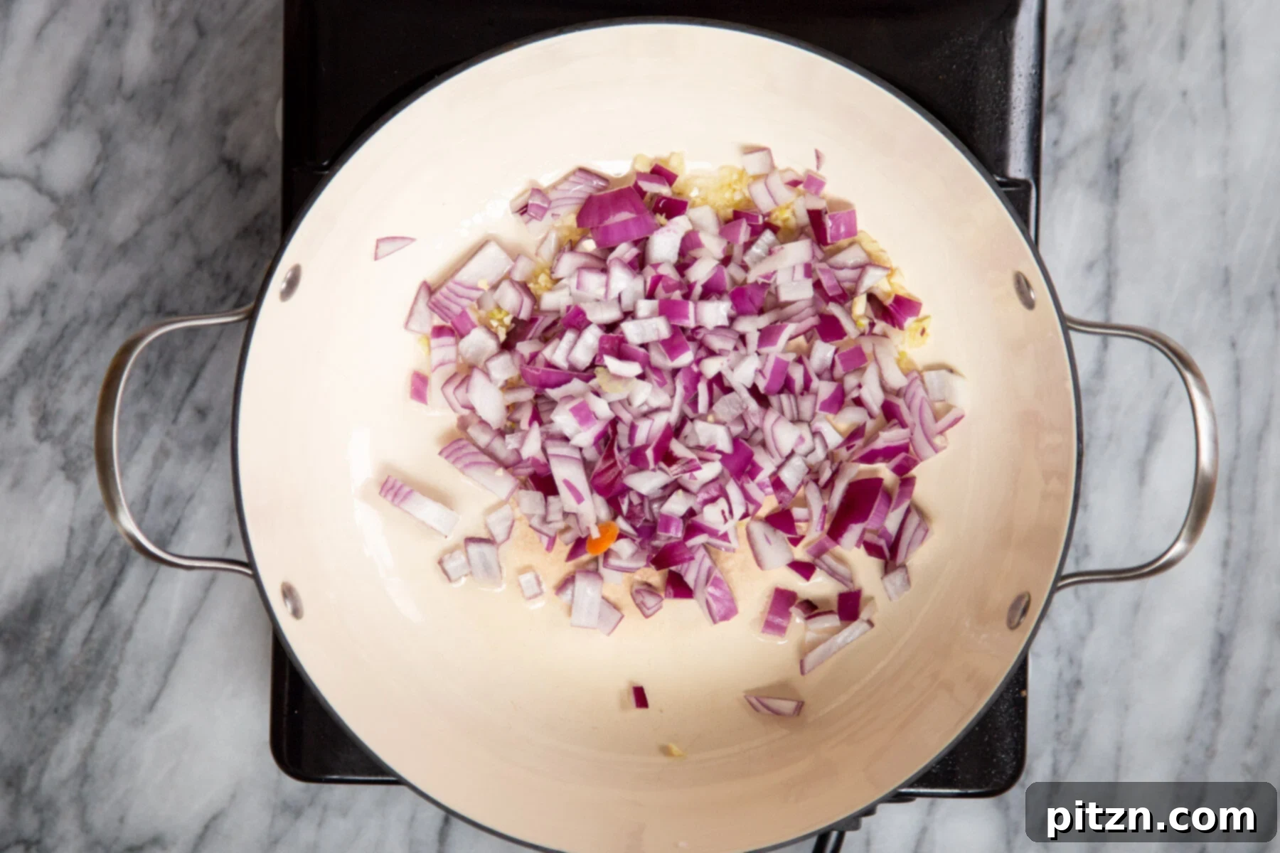 Chopped onions and minced garlic sautéing in a pan, releasing their aromatic flavors as they cook.