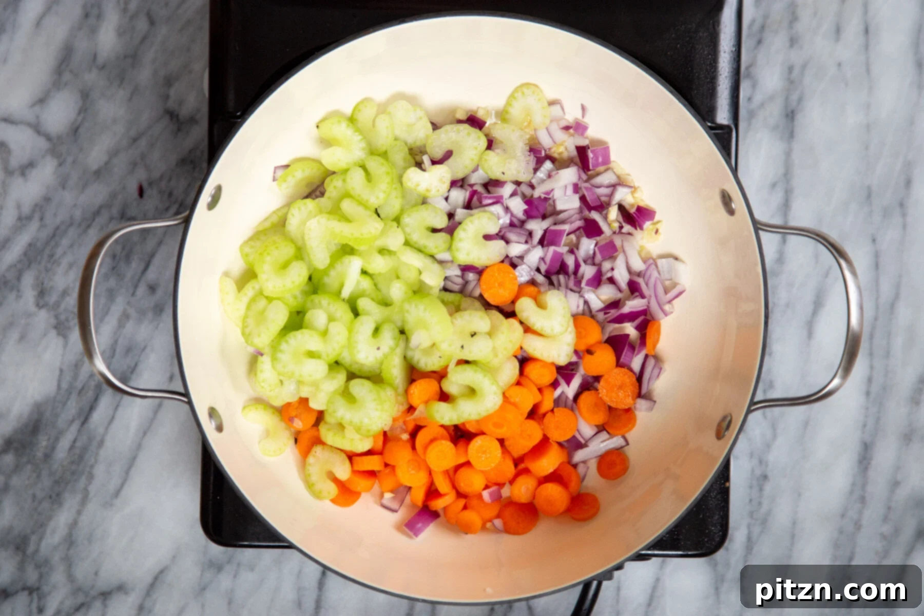 Celery, carrots, and onions cooking together in a sauté pan, creating the foundational flavors for the stew.