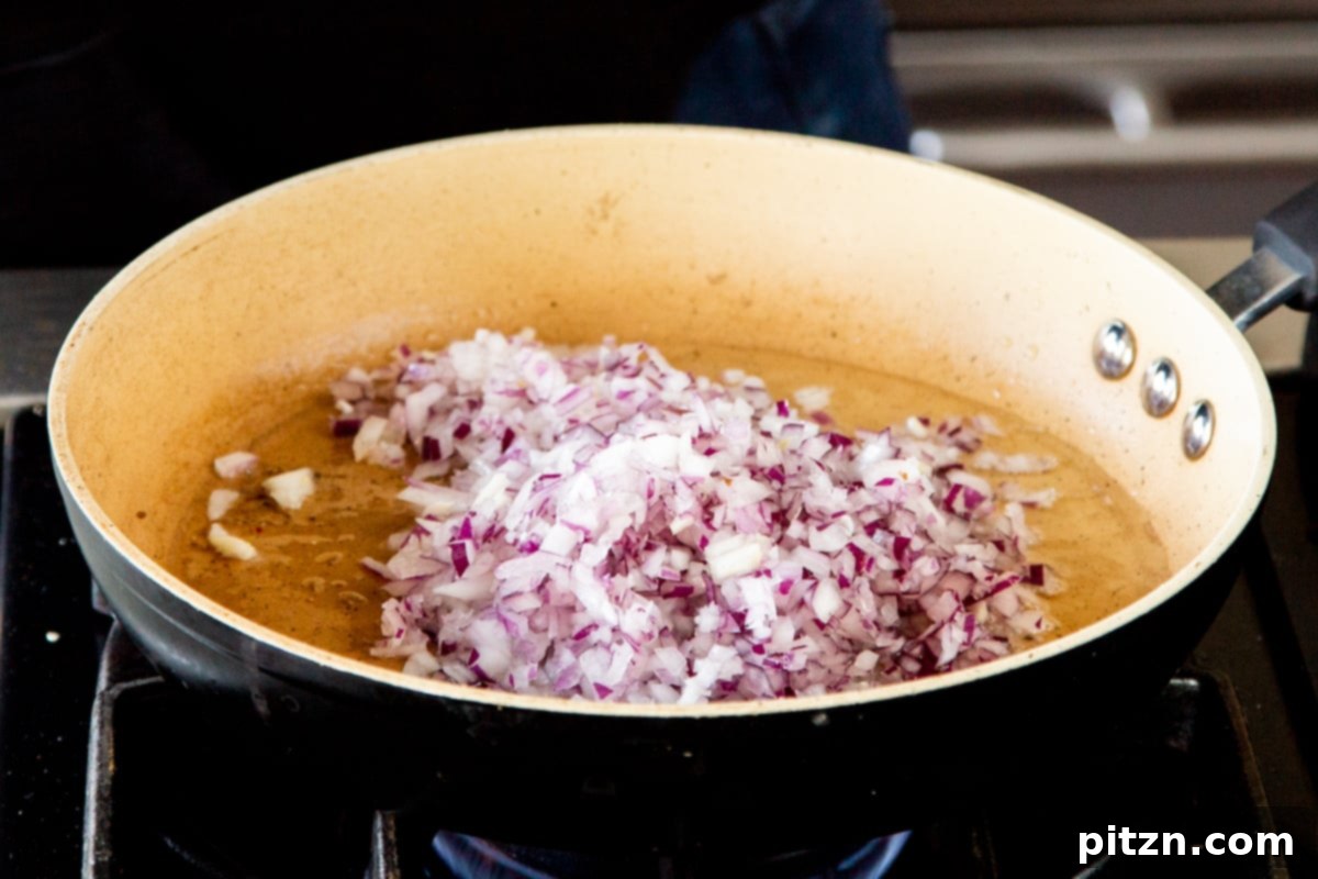 Caramelized Onion Lentil Stew 11 Finely minced onions gently sautéing in a small amount of oil within a frying pan, beginning to soften and turn translucent for the flavorful dal base.