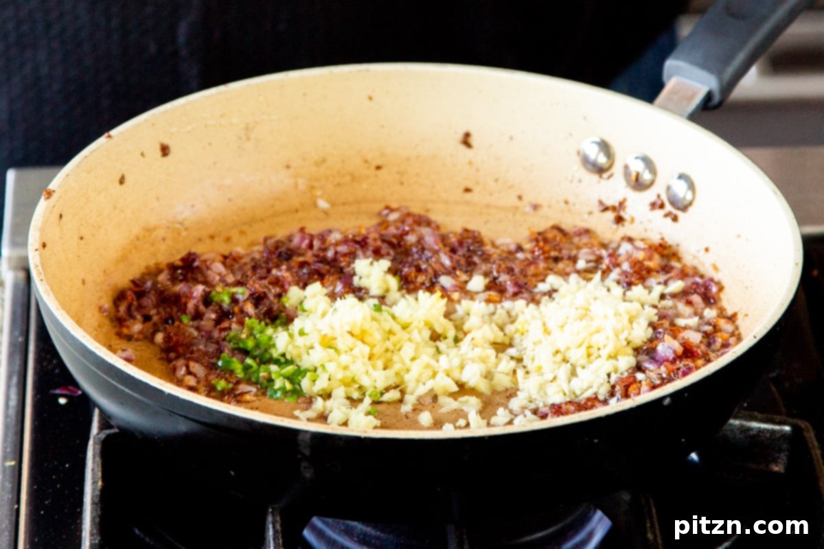 Caramelized Onion Lentil Stew 13 Minced ginger and vibrant green chili, alongside golden caramelized onions, gently sautéing in a frying pan, creating an aromatic and flavorful base for the dal.