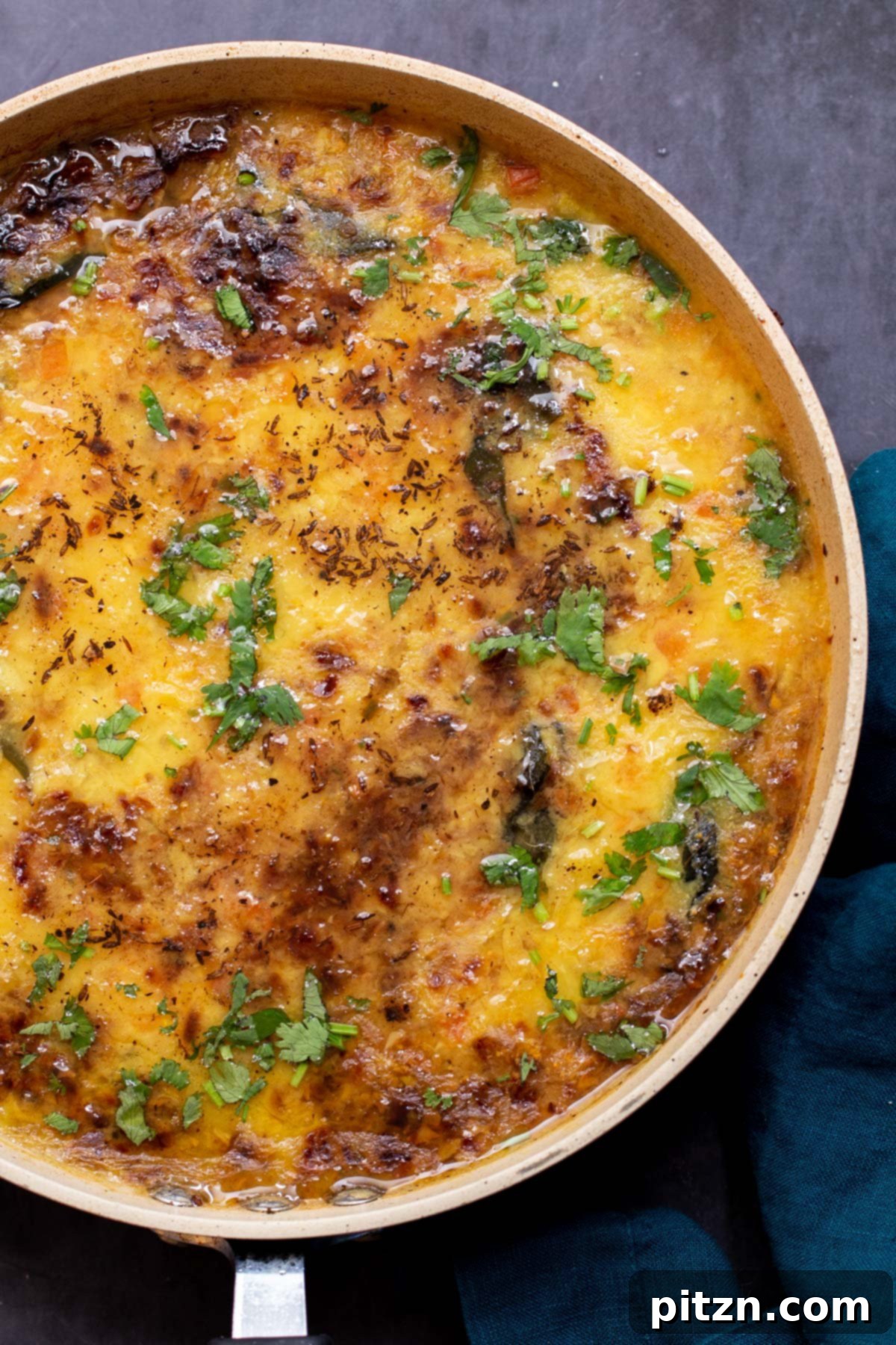 Caramelized Onion Lentil Stew 3 A vibrant close-up of Caramelized Onion Dal simmering in a frying pan, generously sprinkled with freshly chopped cilantro, highlighting its creamy texture and rich color.