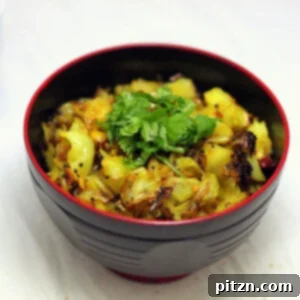 A dark bowl of patta gobi sabzi on a marble countertop