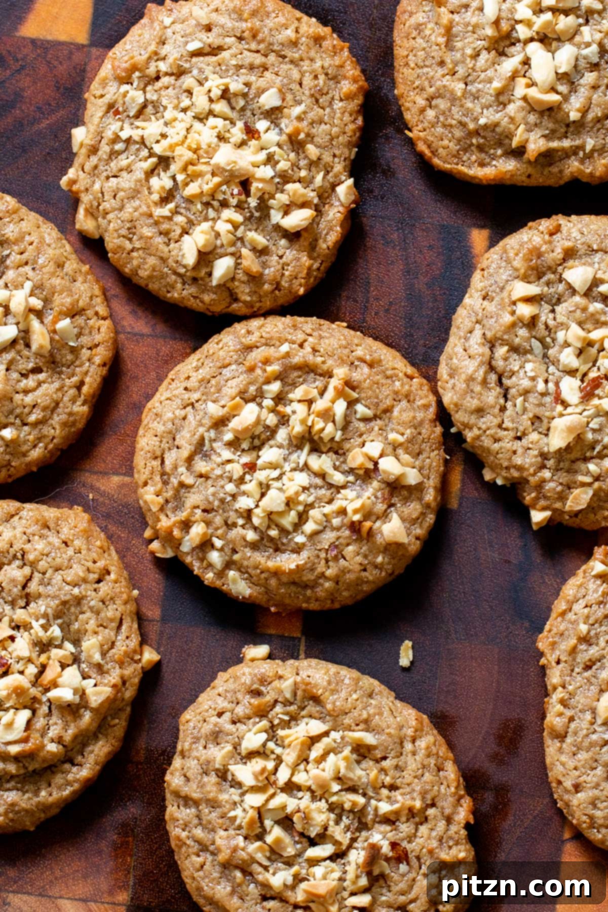 Flourless Peanut Butter Cookies 2 Overhead shot of freshly baked vegan flourless peanut butter cookies, sprinkled generously with crunchy chopped peanuts, showcasing their golden-brown edges and soft centers.