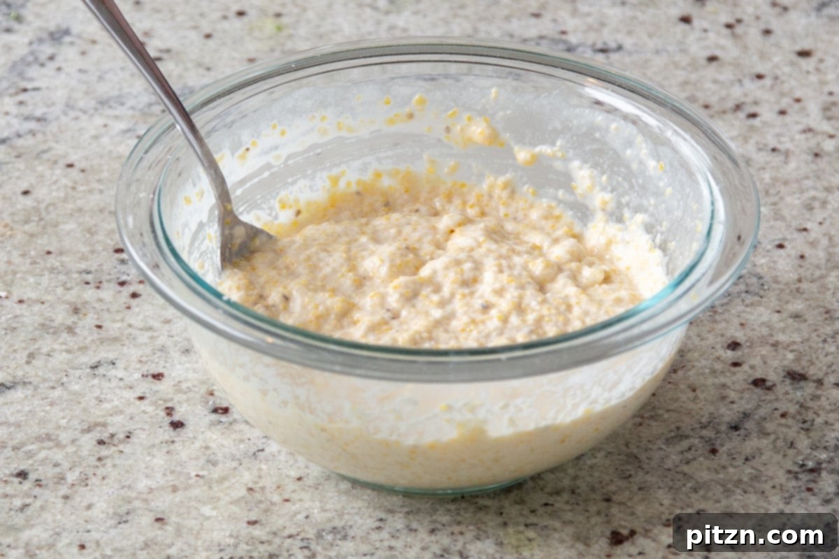 The prepared cornbread topping batter resting in a glass bowl, ready to be spread over the saag.