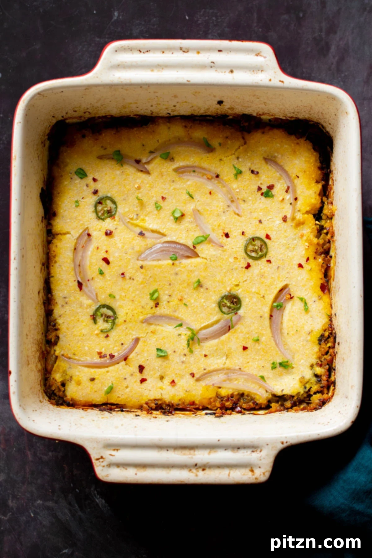 An inviting overhead shot of the vegan Saag Cornbread Casserole, with the golden cornbread topping perfectly baked over the green saag stew in a baking dish.