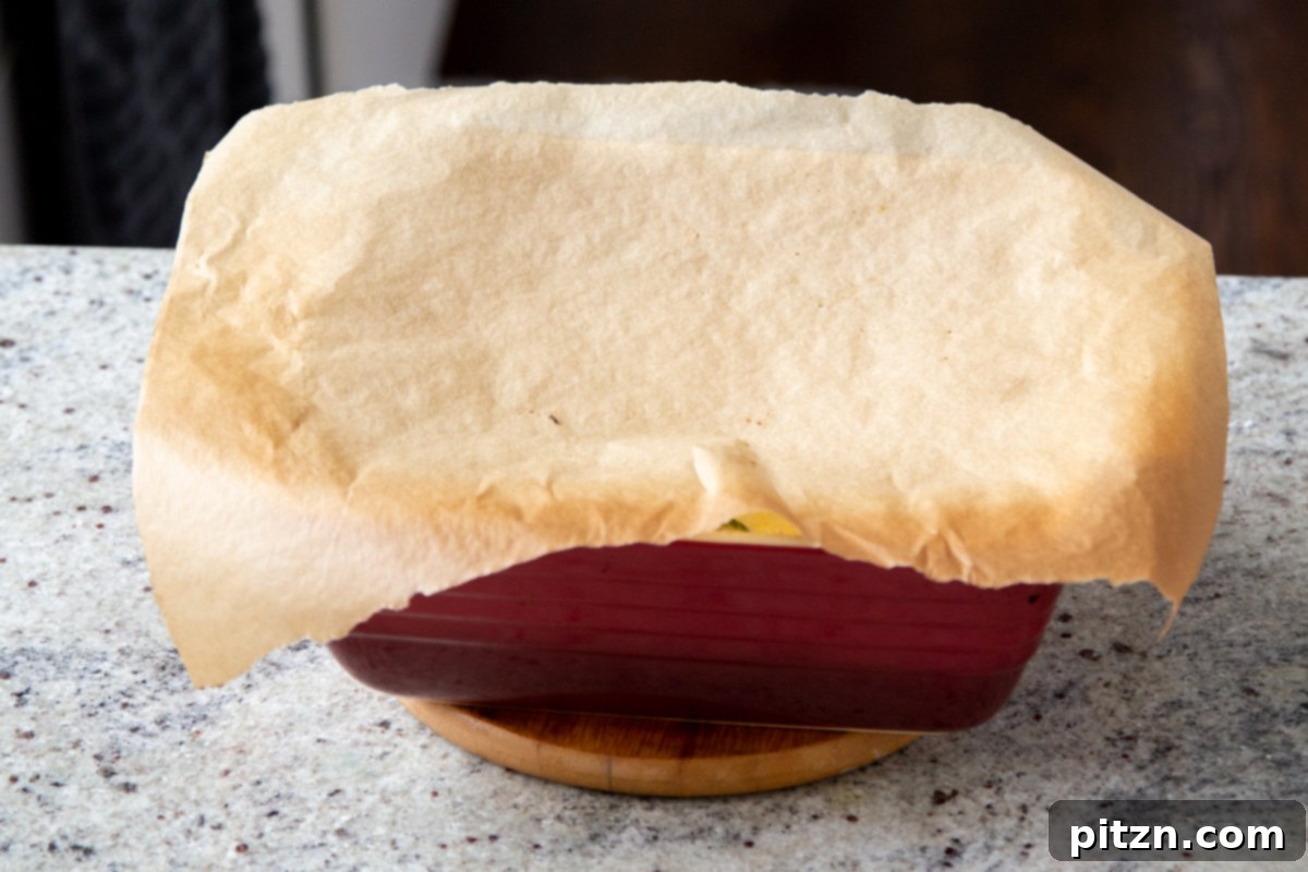 A casserole dish covered with a piece of parchment paper, ready for its final bake to cook the cornbread topping.