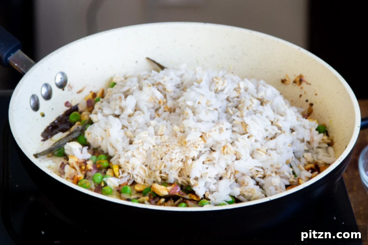 Spiced Onion Poha: Savory Flattened Rice Breakfast 10 The pre-soaked poha flakes and oats being gently folded into the frying pan with the cooked peas, onions, and spices.