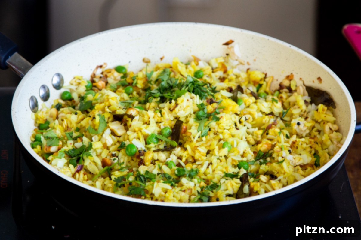 Spiced Onion Poha: Savory Flattened Rice Breakfast 11 A close-up of a pan of finished Kanda Poha, lightly steamed and sprinkled with vibrant chopped cilantro before serving.