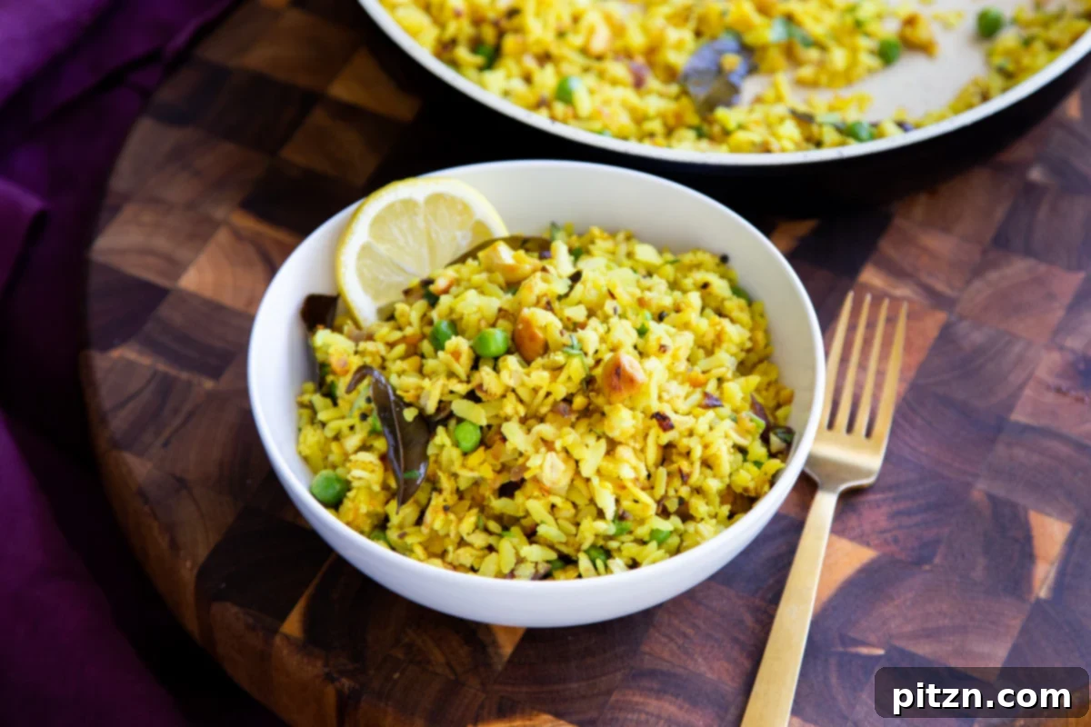 Spiced Onion Poha: Savory Flattened Rice Breakfast 12 A small white bowl filled with freshly prepared Kanda Poha, garnished with a slice of lemon and fresh cilantro, ready for consumption.