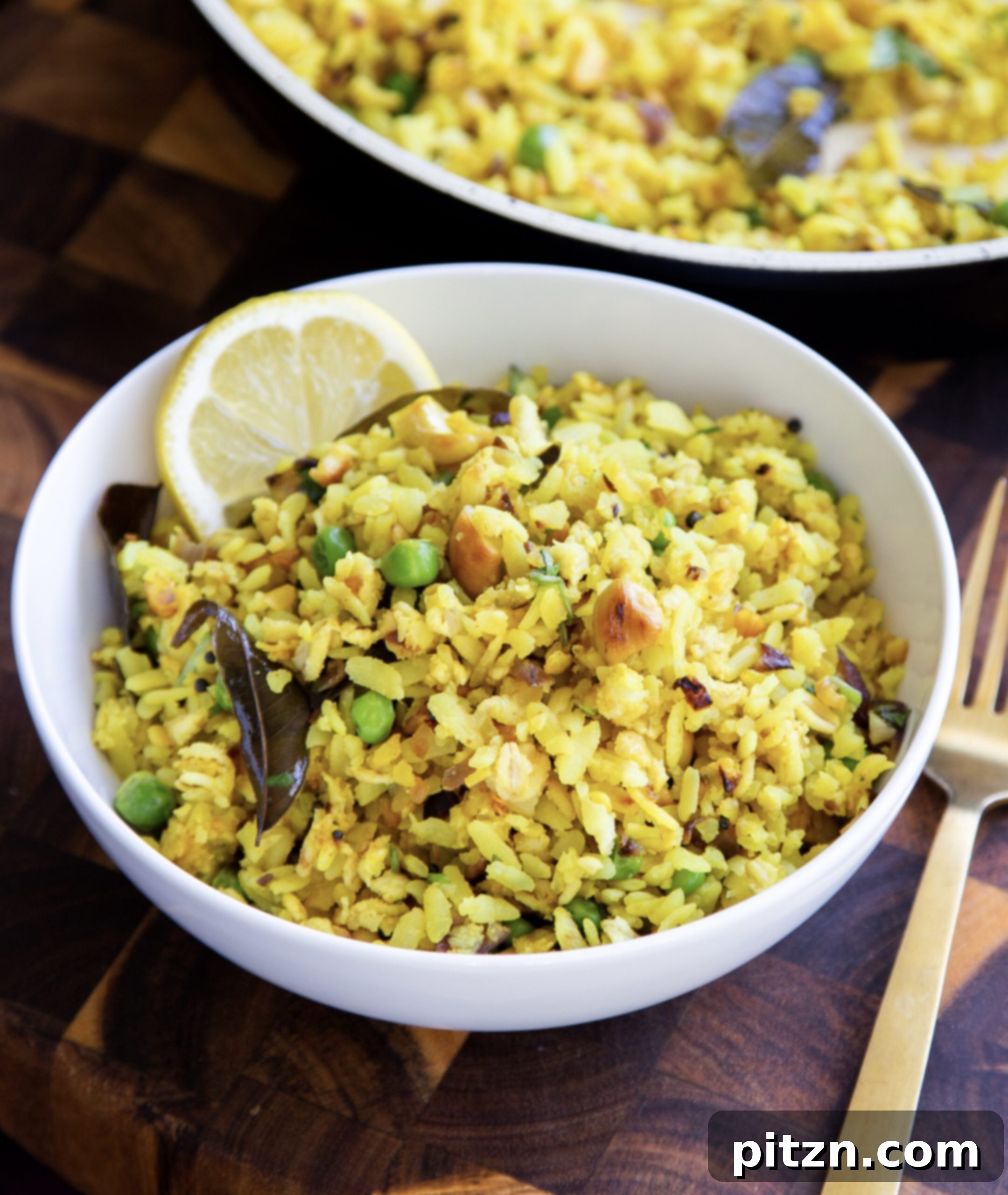 Spiced Onion Poha: Savory Flattened Rice Breakfast 3 A beautifully presented bowl of Indian Kanda Poha, garnished with fresh cilantro and a lime wedge, ready to be enjoyed.