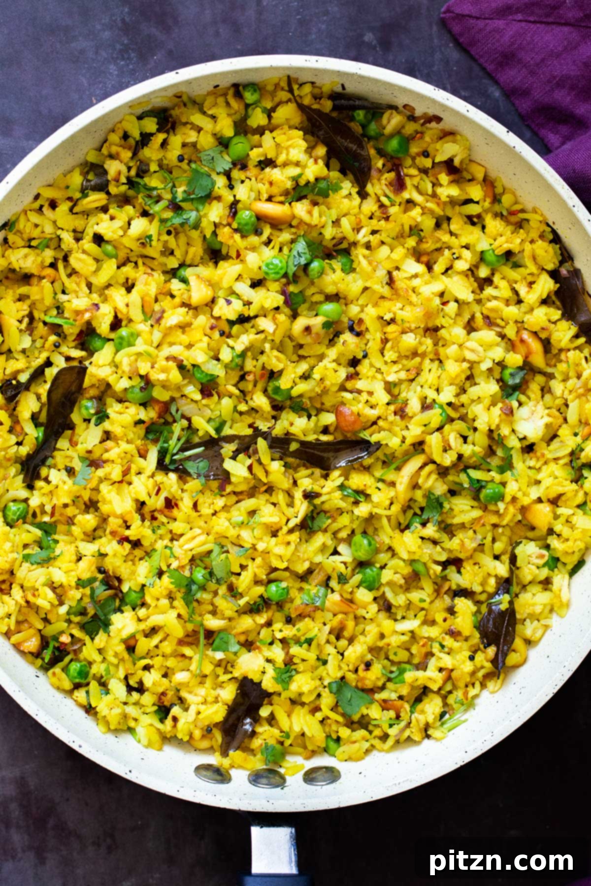 Spiced Onion Poha: Savory Flattened Rice Breakfast 4 A frying pan on a stovetop, capturing the cooking process of Indian Kanda Poha, with onions and spices sizzling gently.