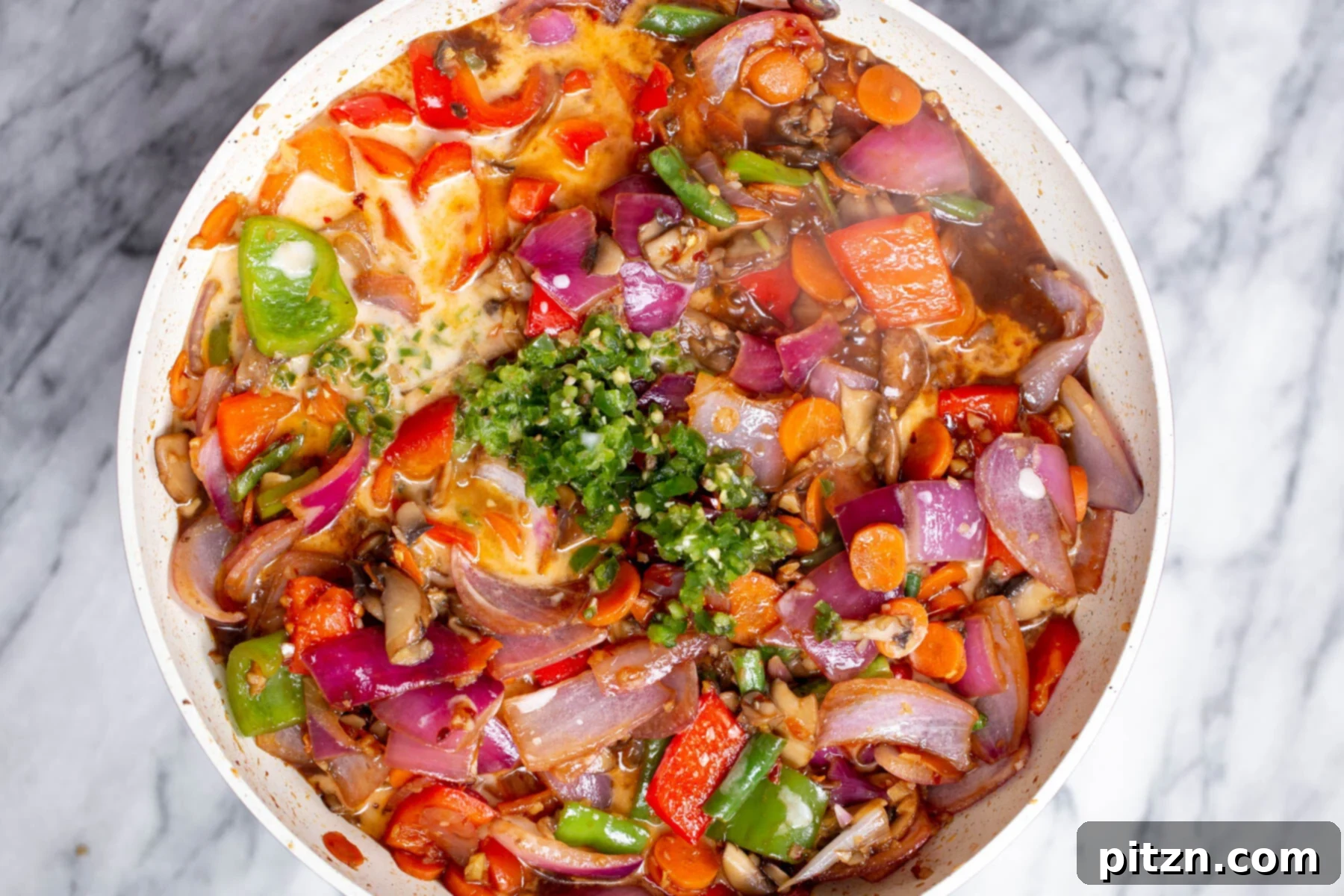 Blazing Garlic Vegetable Medley 13 More minced green chili is being incorporated into the saucepan filled with vegetables and the simmering sweet and sour sauce, ensuring even distribution of heat.