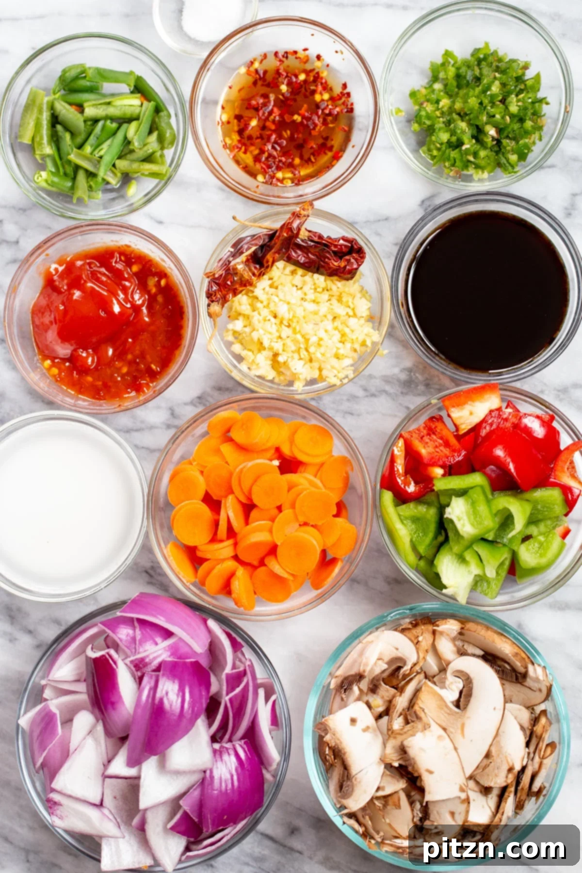 Blazing Garlic Vegetable Medley 6 A beautiful array of fresh ingredients for Veggies in Hot Garlic Sauce, laid out on a marble countertop, including various colorful vegetables, garlic, ginger, and sauces.