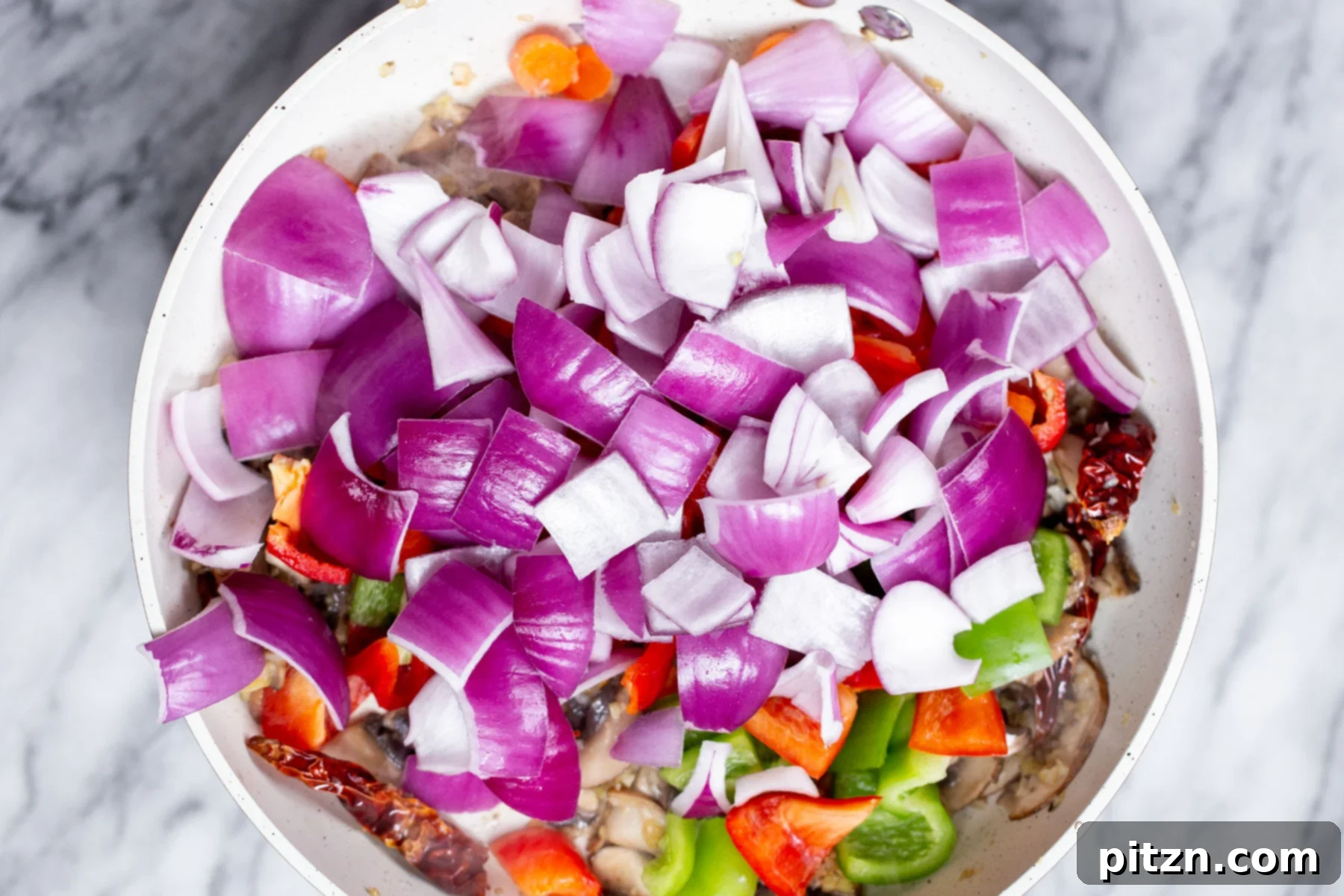 Blazing Garlic Vegetable Medley 9 A mix of freshly chopped vegetables, including onions and bell peppers, being stir-fried in a hot pan.