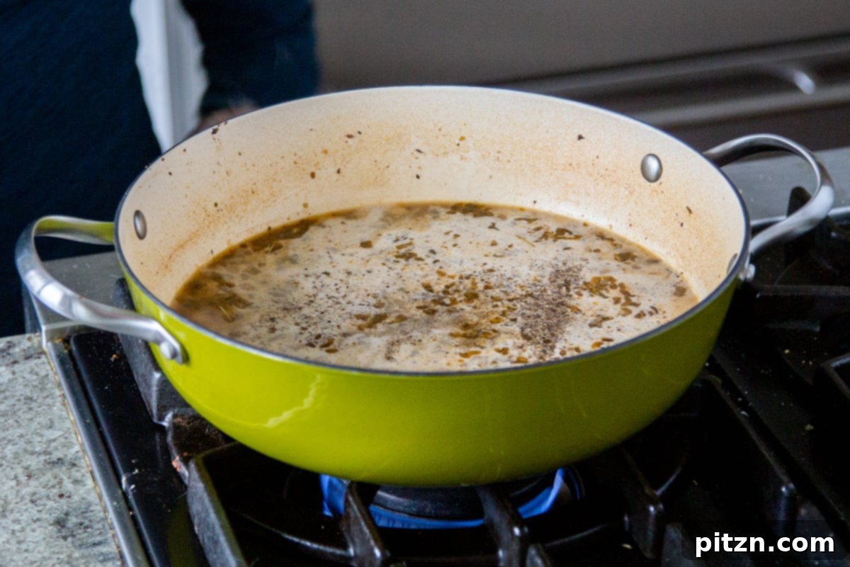 Cashew cream being poured into a saucepan of simmering vegan Zuppa Toscana, with vegetables and crumbles.