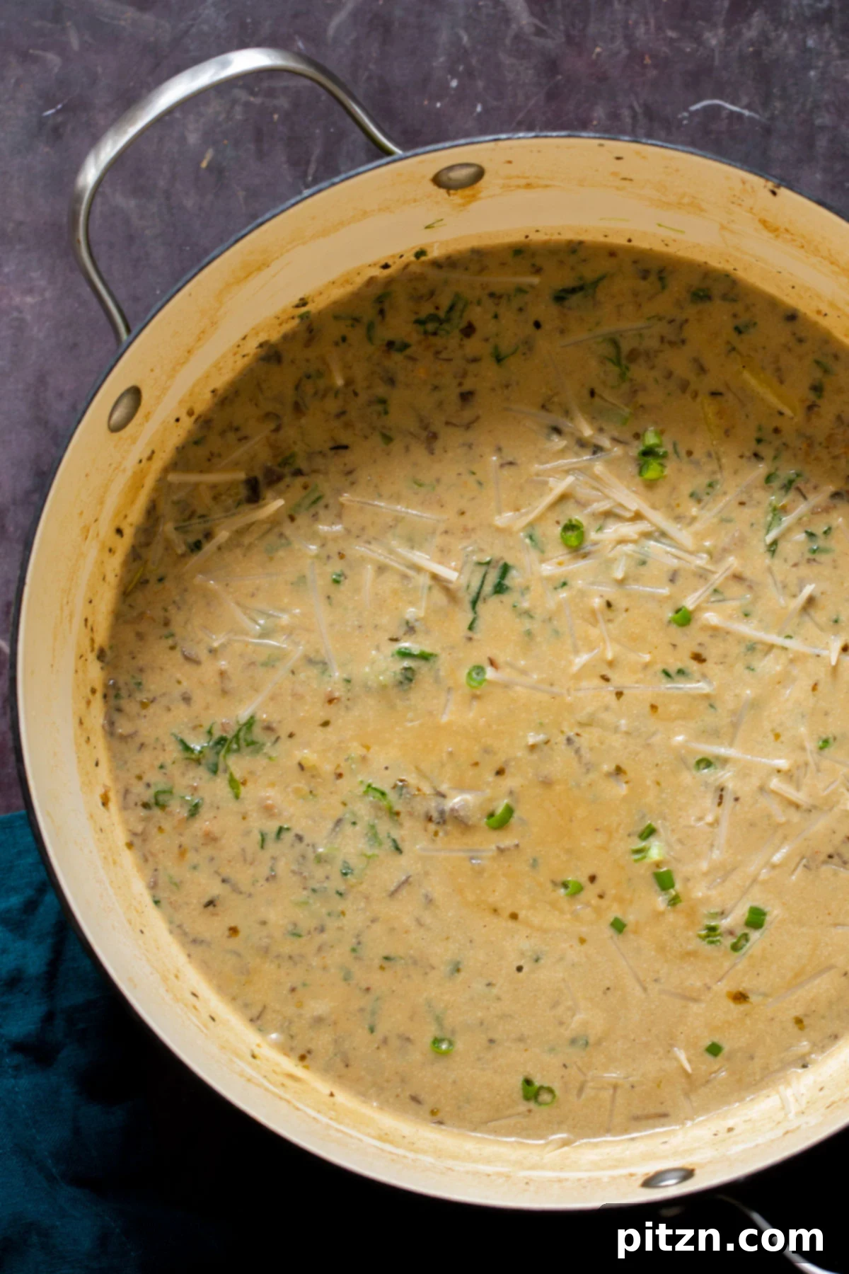 A large pot of creamy vegan Zuppa Toscana, topped with melted shredded vegan cheese, ready to be served.