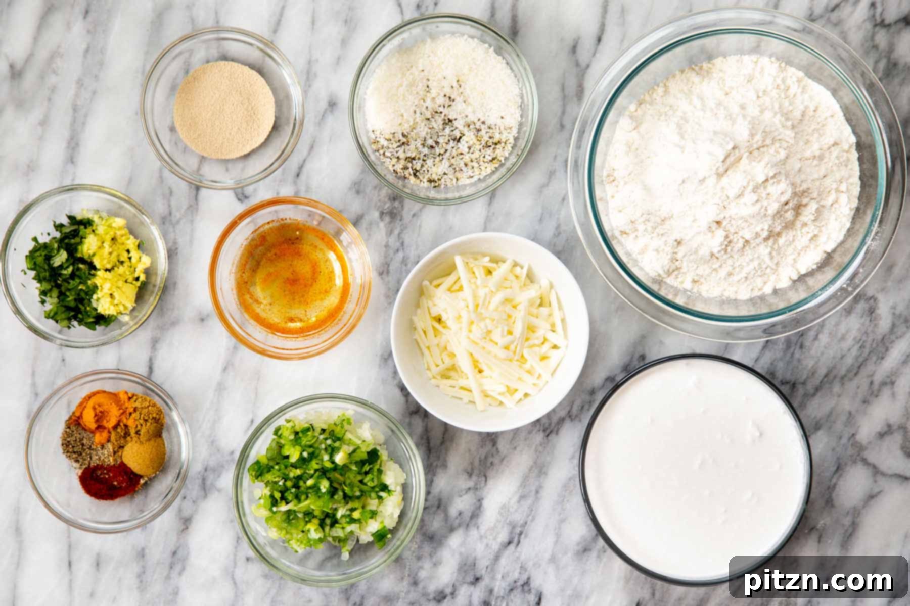 Golden Mustard Coconut Rolls 6 Bowls of flour, vegan cheese, and various spices arranged neatly on a marble countertop, showcasing the raw ingredients.