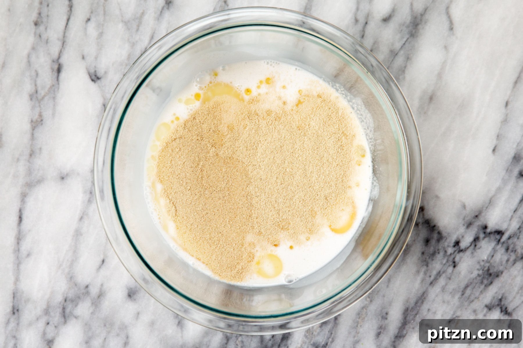 Golden Mustard Coconut Rolls 7 Mixing warm non-dairy milk with oil and yeast in a bowl to activate the yeast.