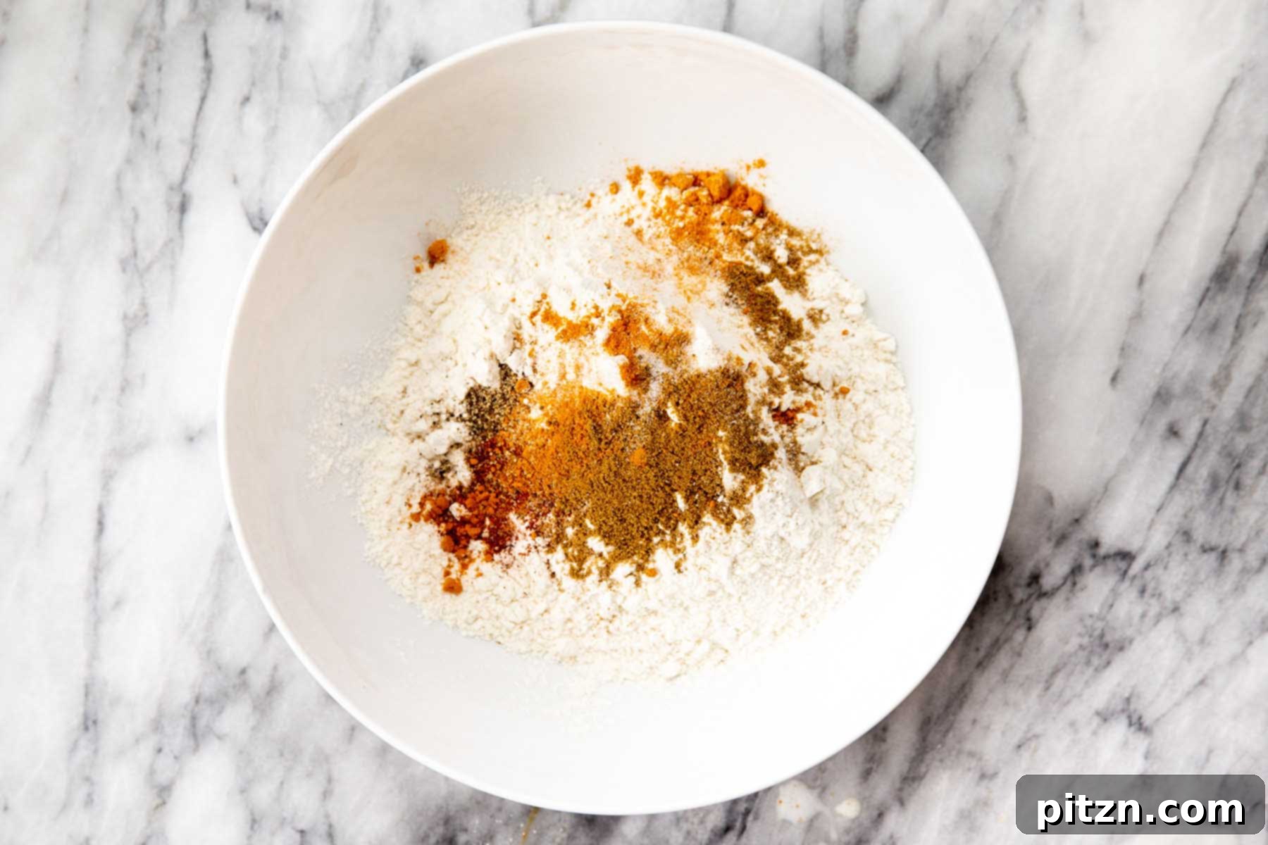 Golden Mustard Coconut Rolls 9 A bowl containing flour and various Indian spices being mixed together.