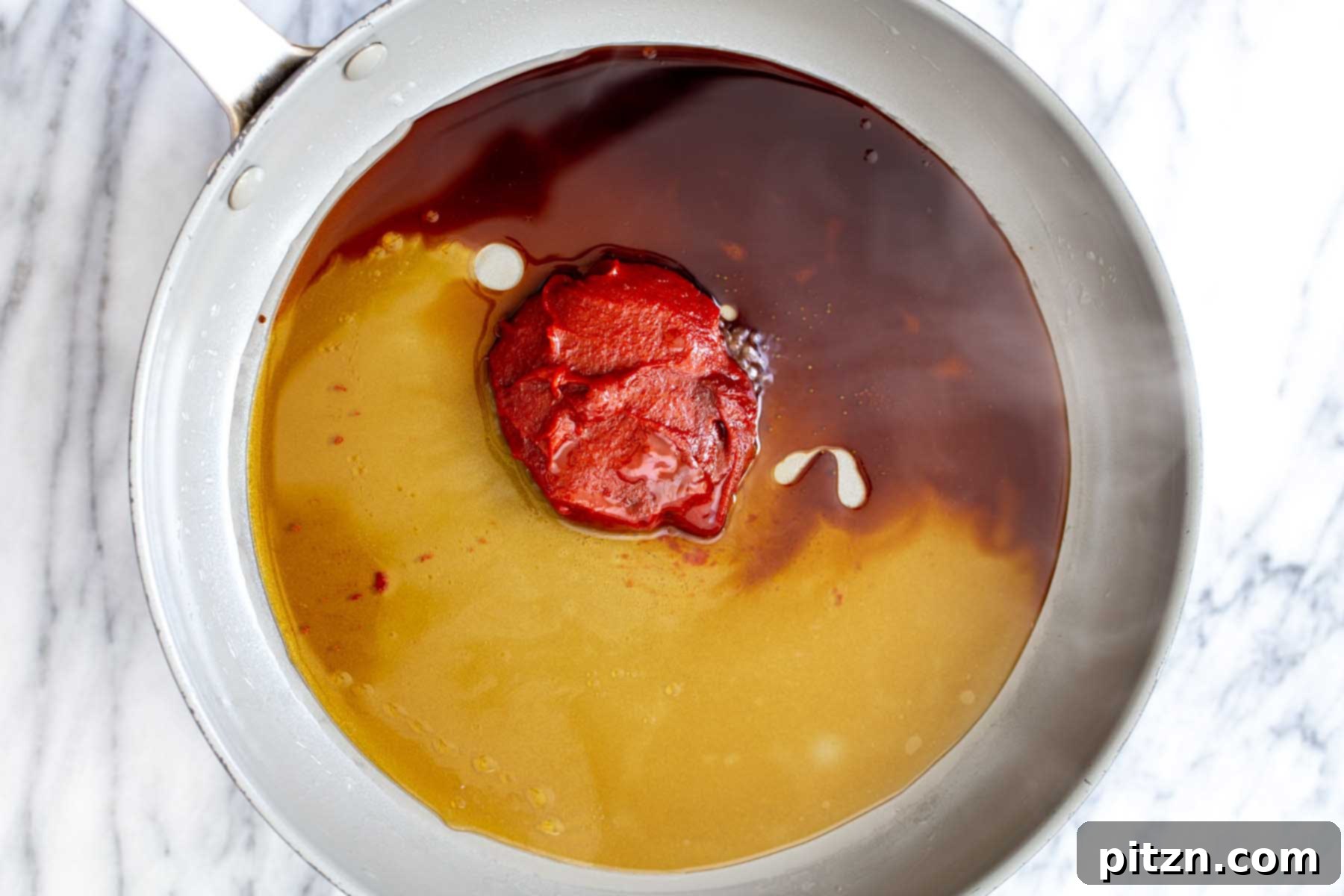 Gochujang sauce ingredients, including the chili paste, soy sauce, and maple syrup, combined in a pan before heating and thickening.