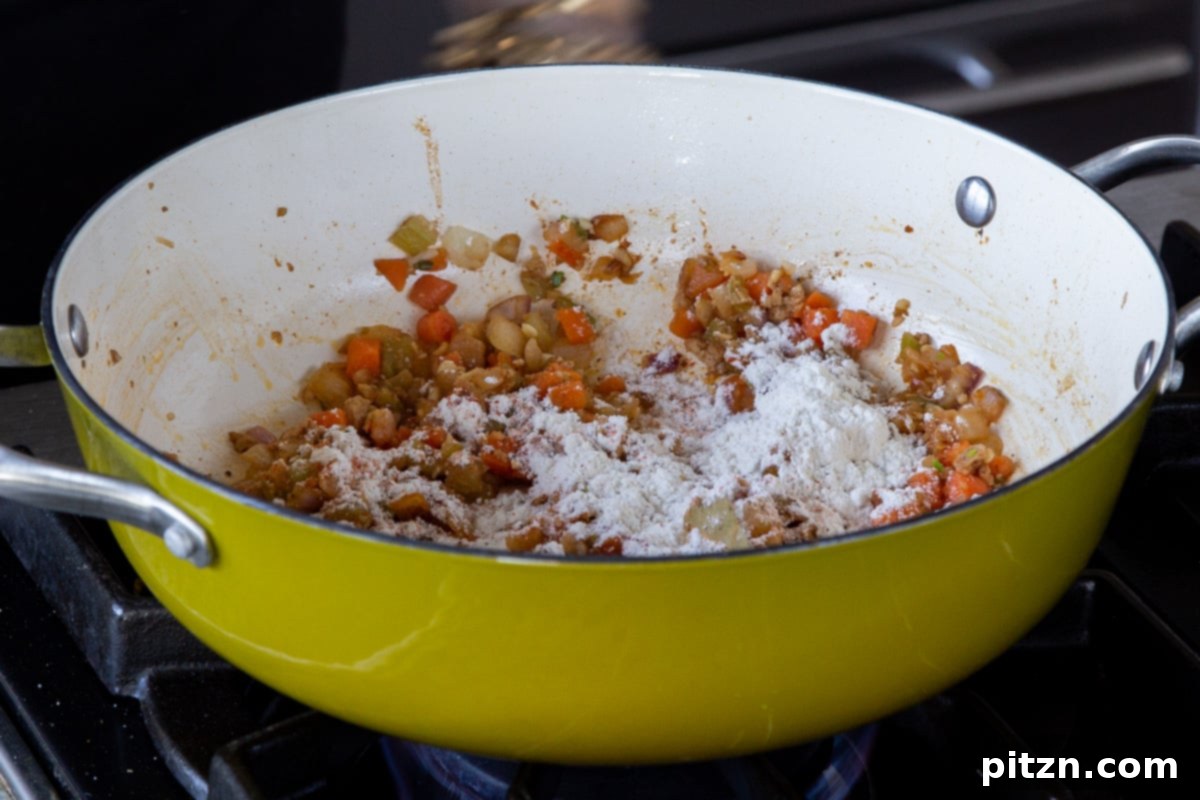 Fireside Smoked Potato Soup 12 All-purpose flour being sprinkled over the sautéed vegetables in the pan to create a roux for the soup base